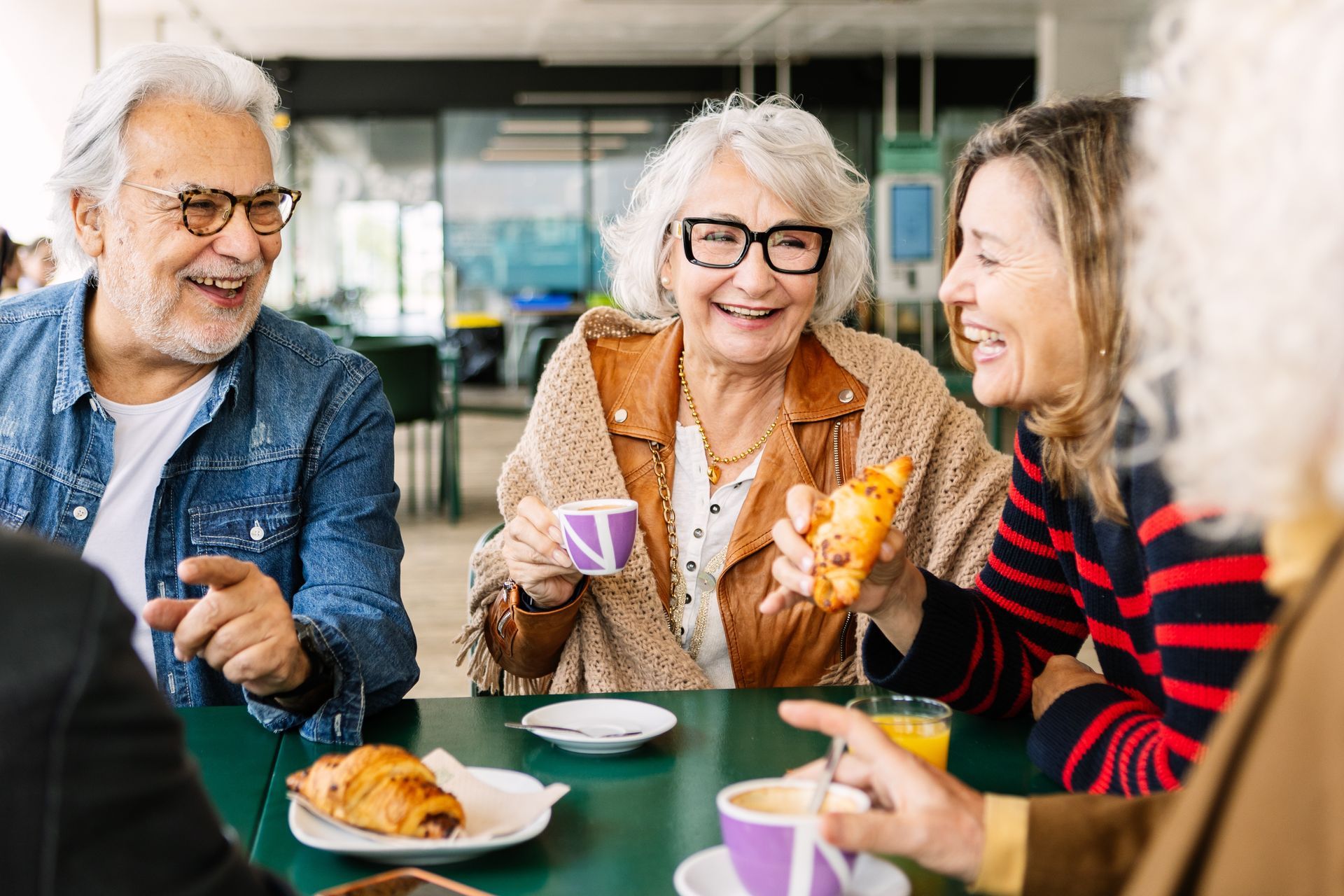 Three friends chatting over coffee and pastries at a café table
