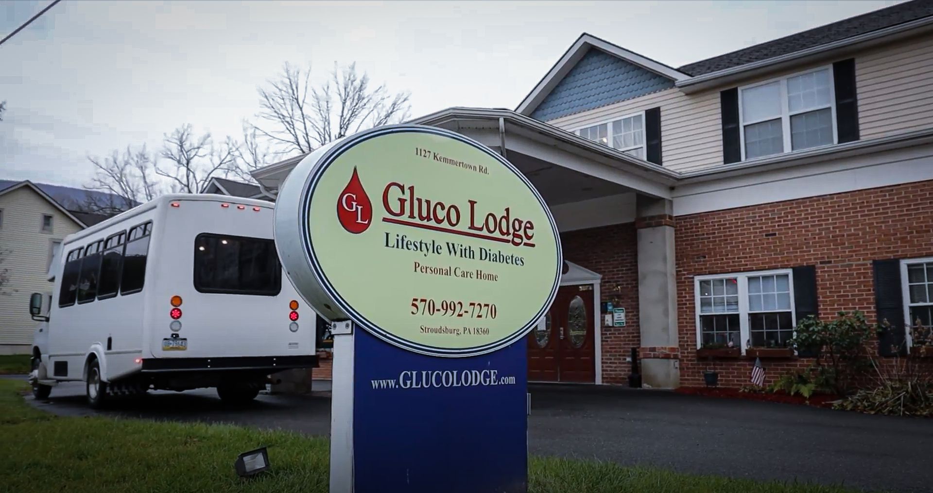 Ghico Lodge sign outside a brick building, with a white van parked nearby.