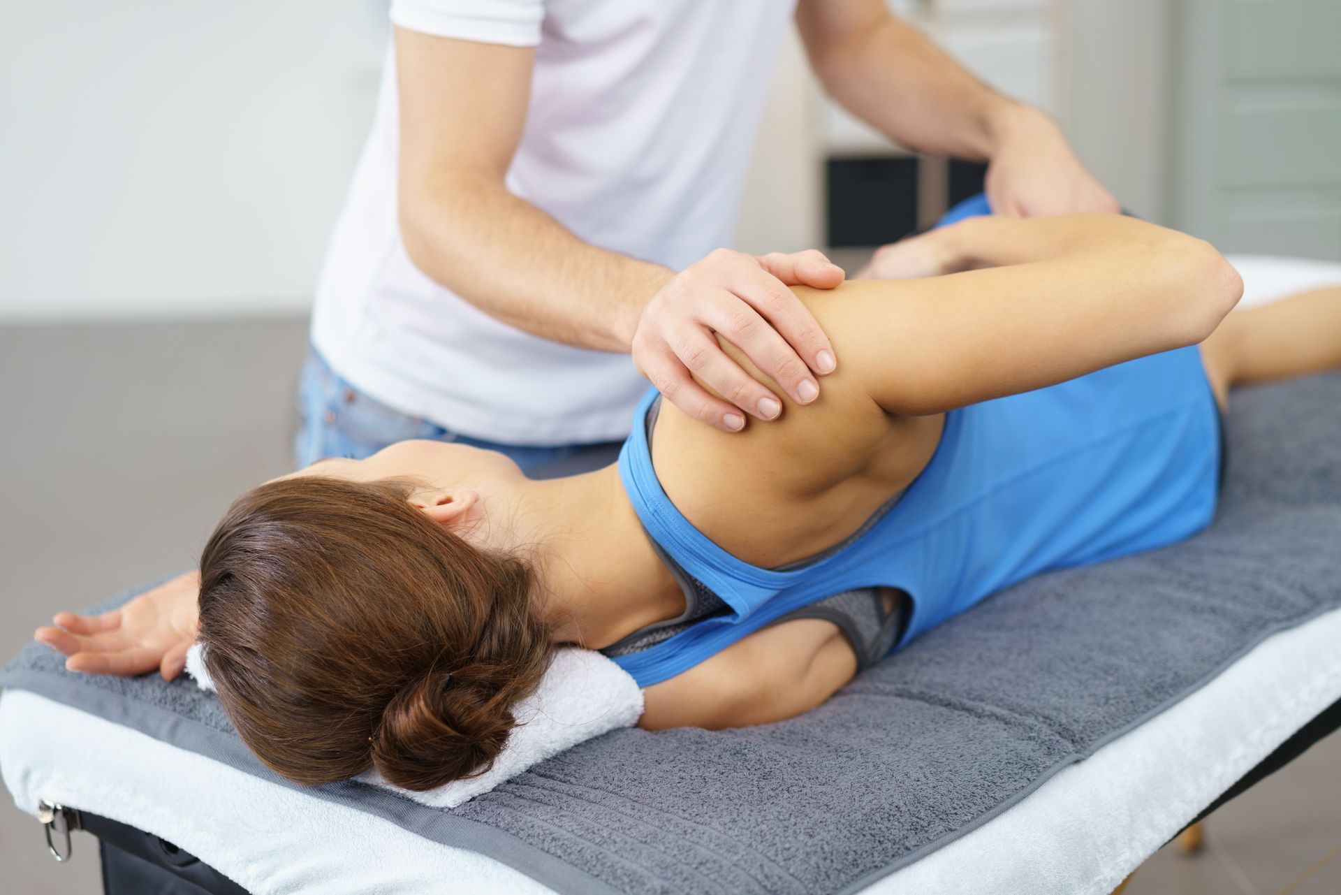 Therapeut streckt den Arm einer Frau auf einem Massagetisch.
