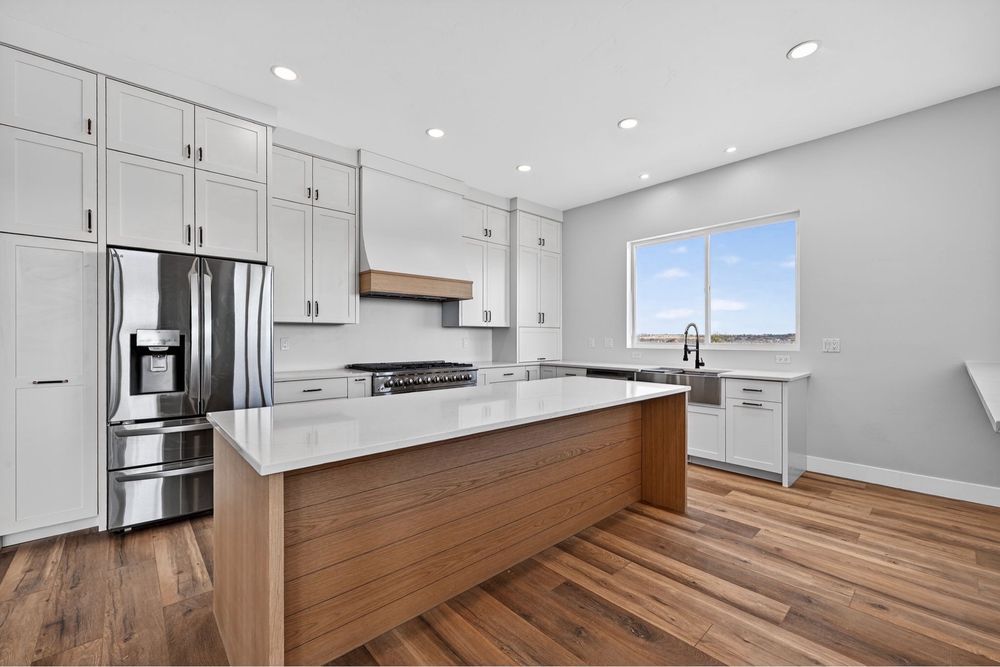 Bright modern kitchen with white cabinets, wood island, stainless appliances, and large window