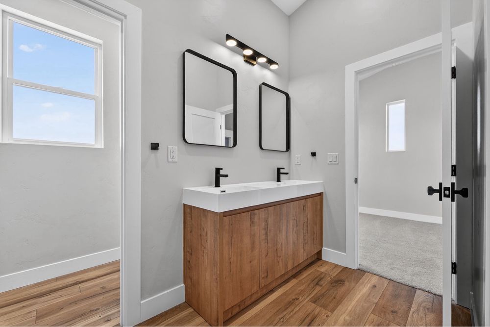 Modern bathroom vanity with black fixtures, wood cabinet, and white walls and tile floor.