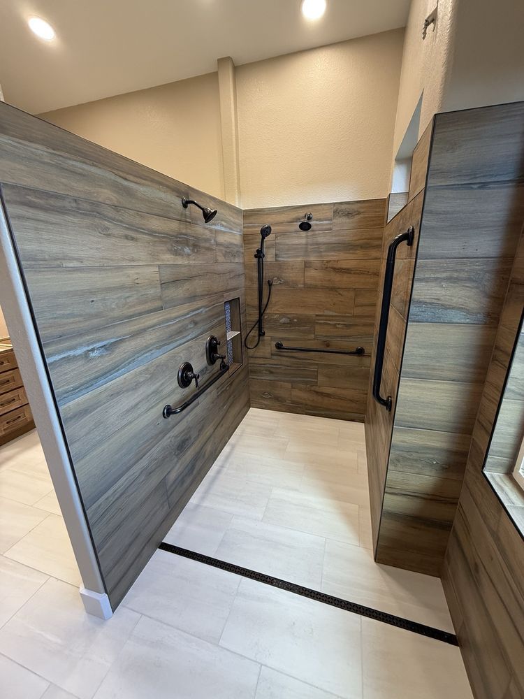 Walk-in shower with wood-look tile walls, beige floor, and multiple black shower fixtures