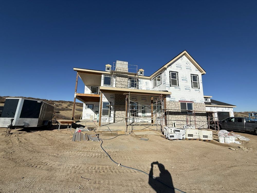 House under construction on a dirt lot under a clear blue sky