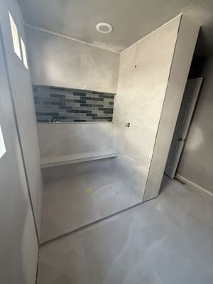 Empty modern kitchen alcove with gray tile backsplash, white walls, and light gray floor