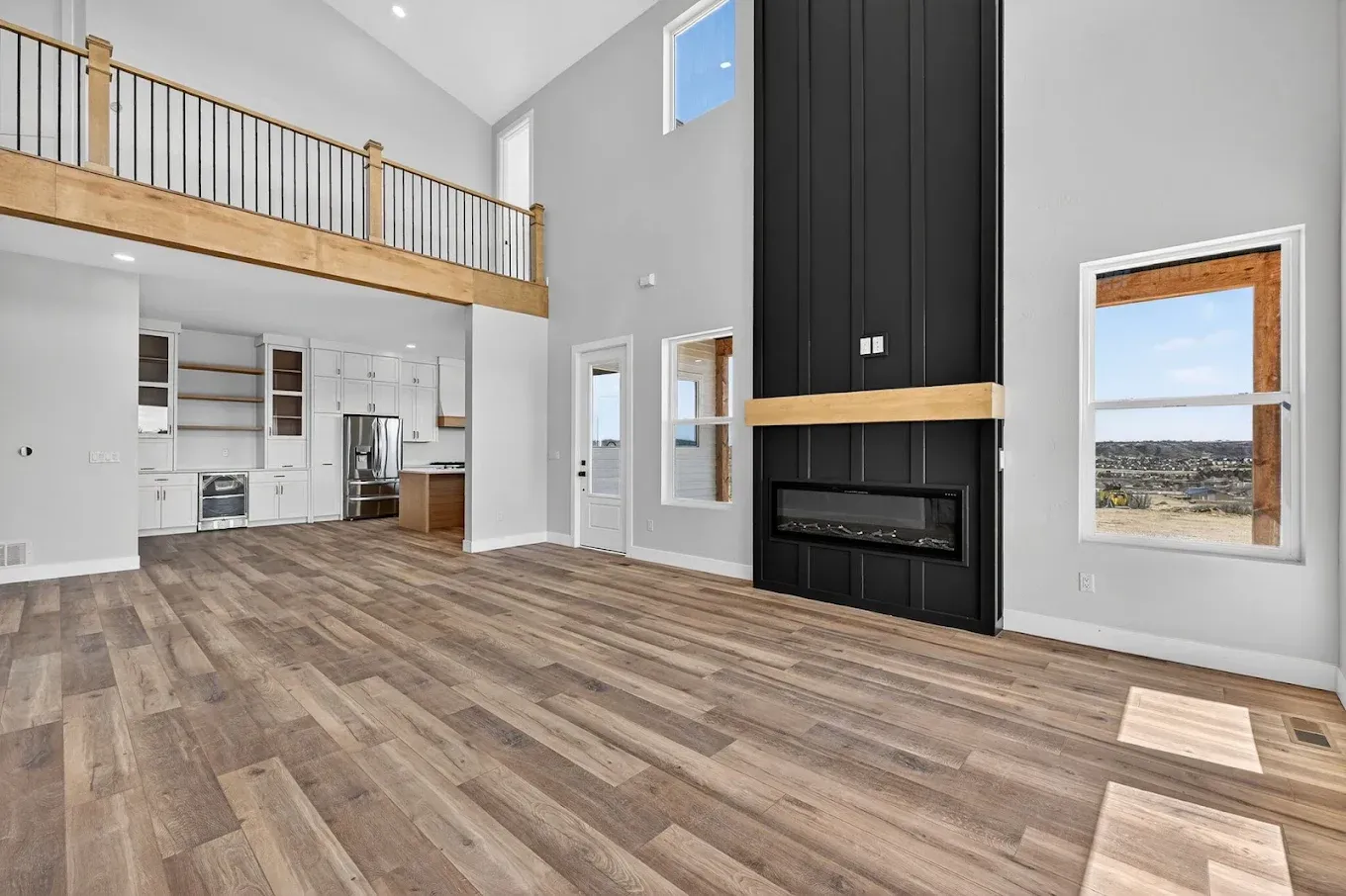 Spacious modern living room with vaulted ceilings, wood floors, and a black fireplace wall