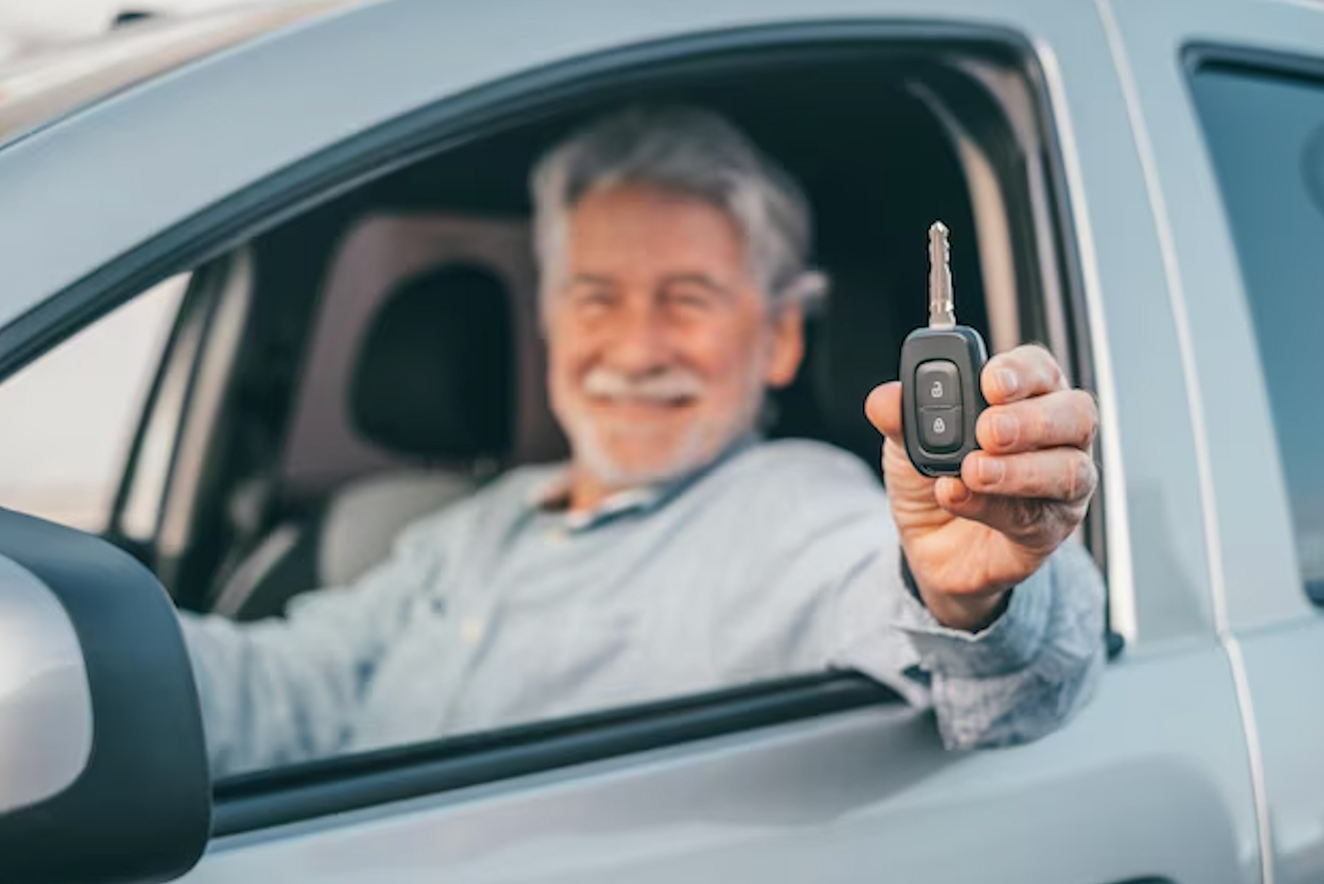 Smiling man in car, holding up car keys.