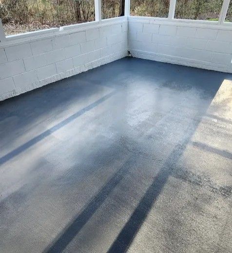 A fresh coat of grey paint on a screened-in porch floor, with shadows cast across the concrete surface.