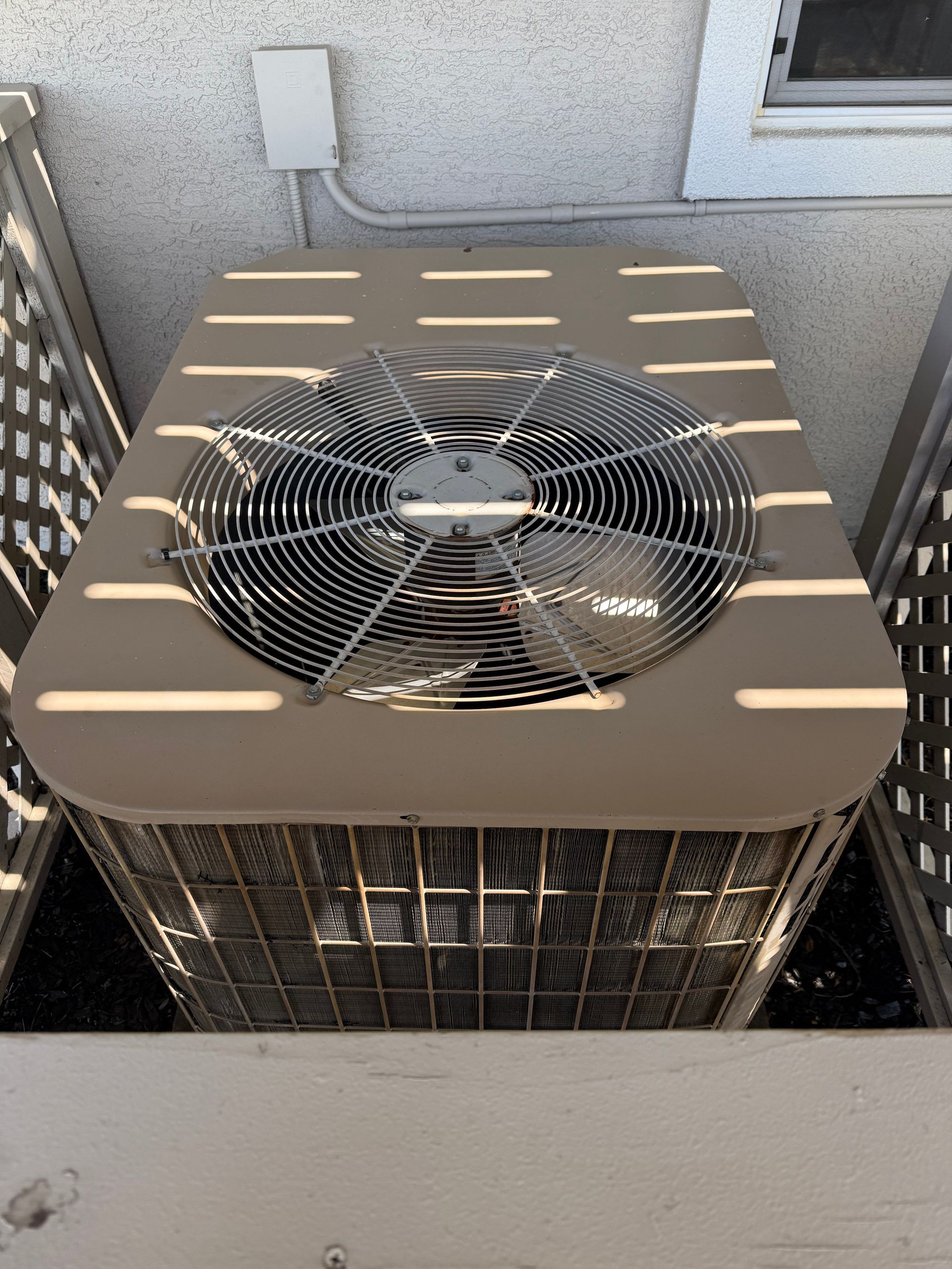 Outdoor air conditioner unit with a top-mounted fan on a balcony