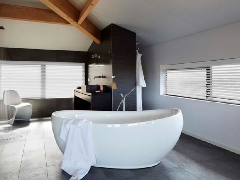 Modern bathroom with a white oval bathtub, blinds, and a white chair. Modern bathroom with a white oval bathtub, blinds, and a white chair.