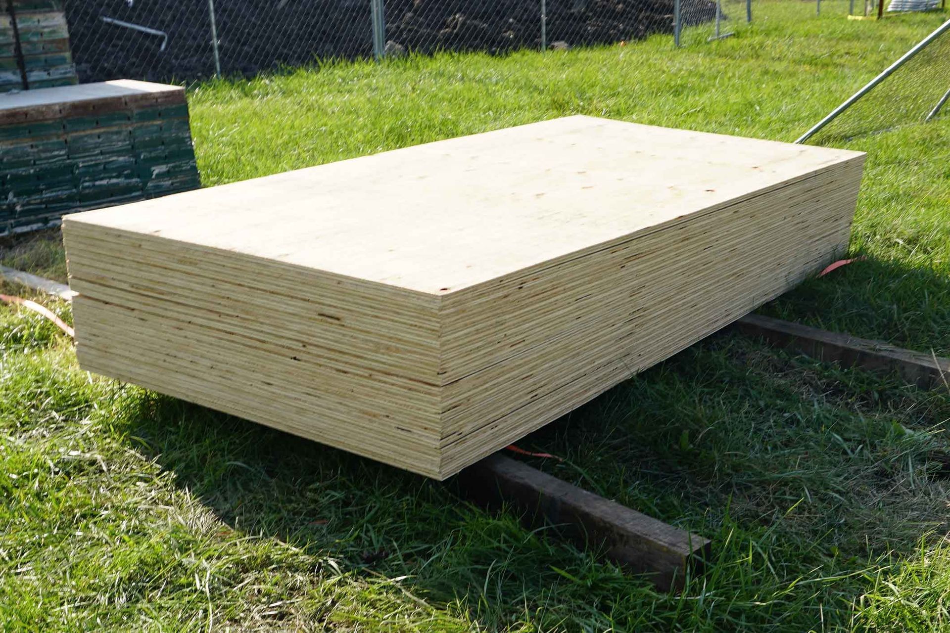 A Stack Of Plywood Is Sitting In The Grass – Beaudesert, QLD - Enrights Sawmill