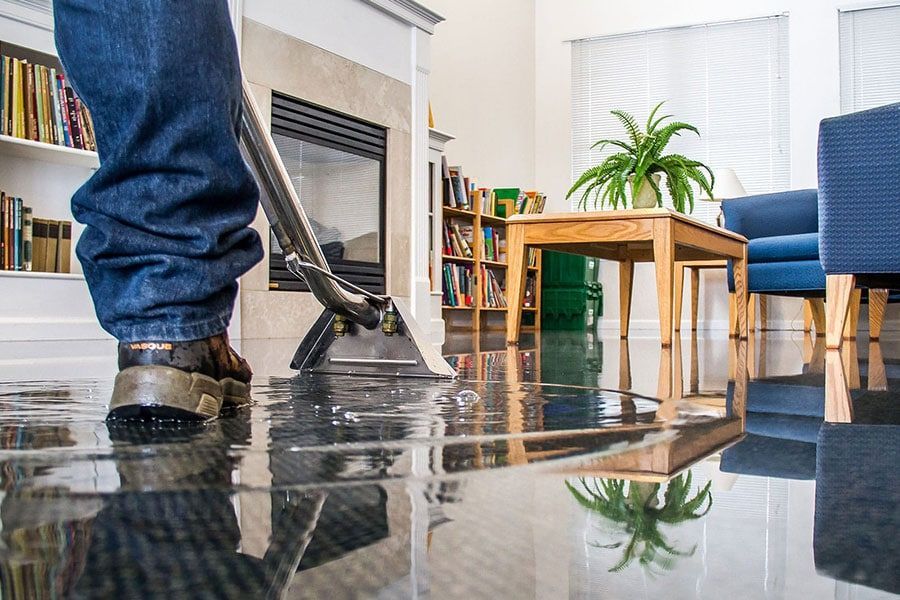 A person using a floor cleaning machine on a shiny, wet floor in a living room with a fireplace and furniture.