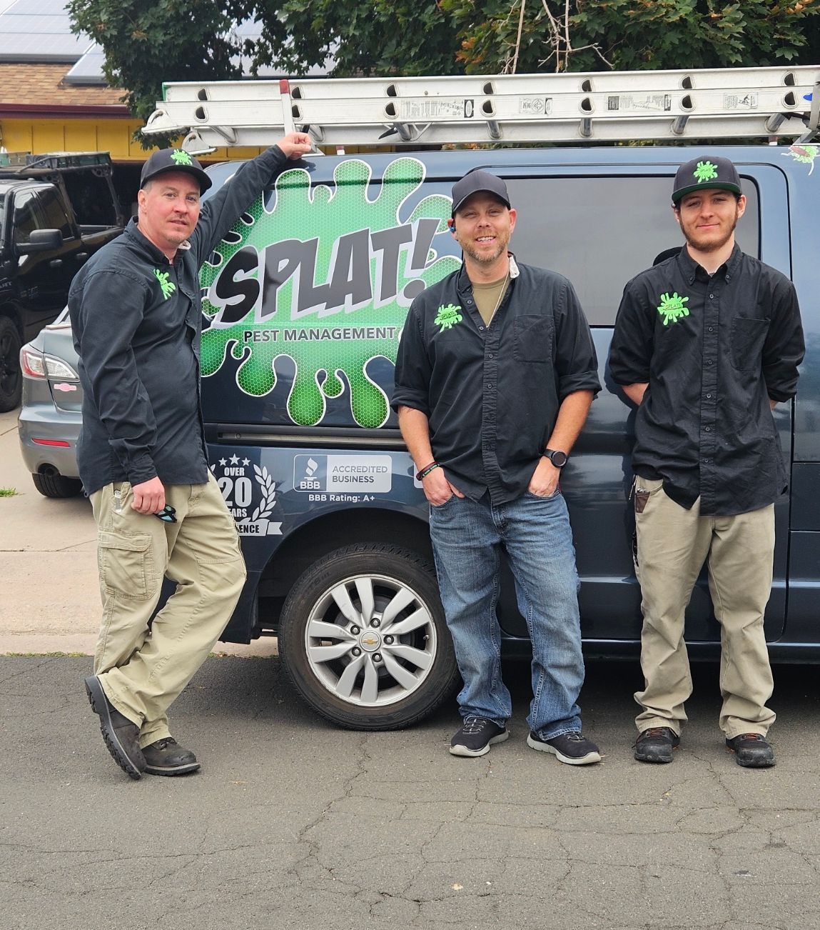 Three men are standing in front of a van that says splat