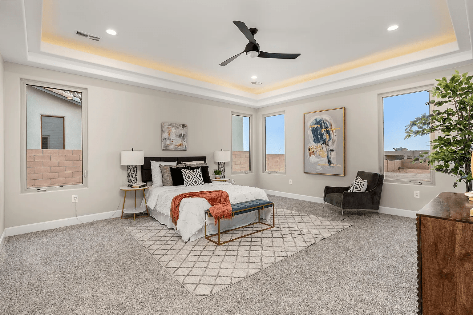A bedroom with a bed , chair , dresser and ceiling fan.