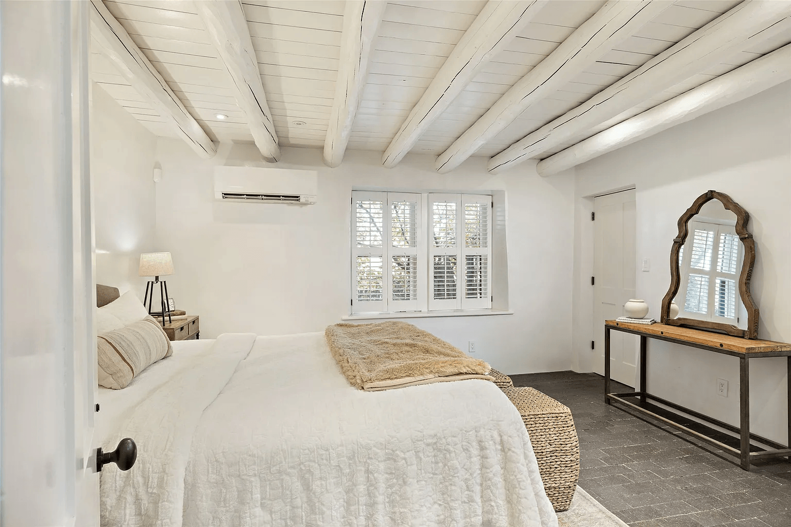A bedroom with a large bed , a mirror , and a window.