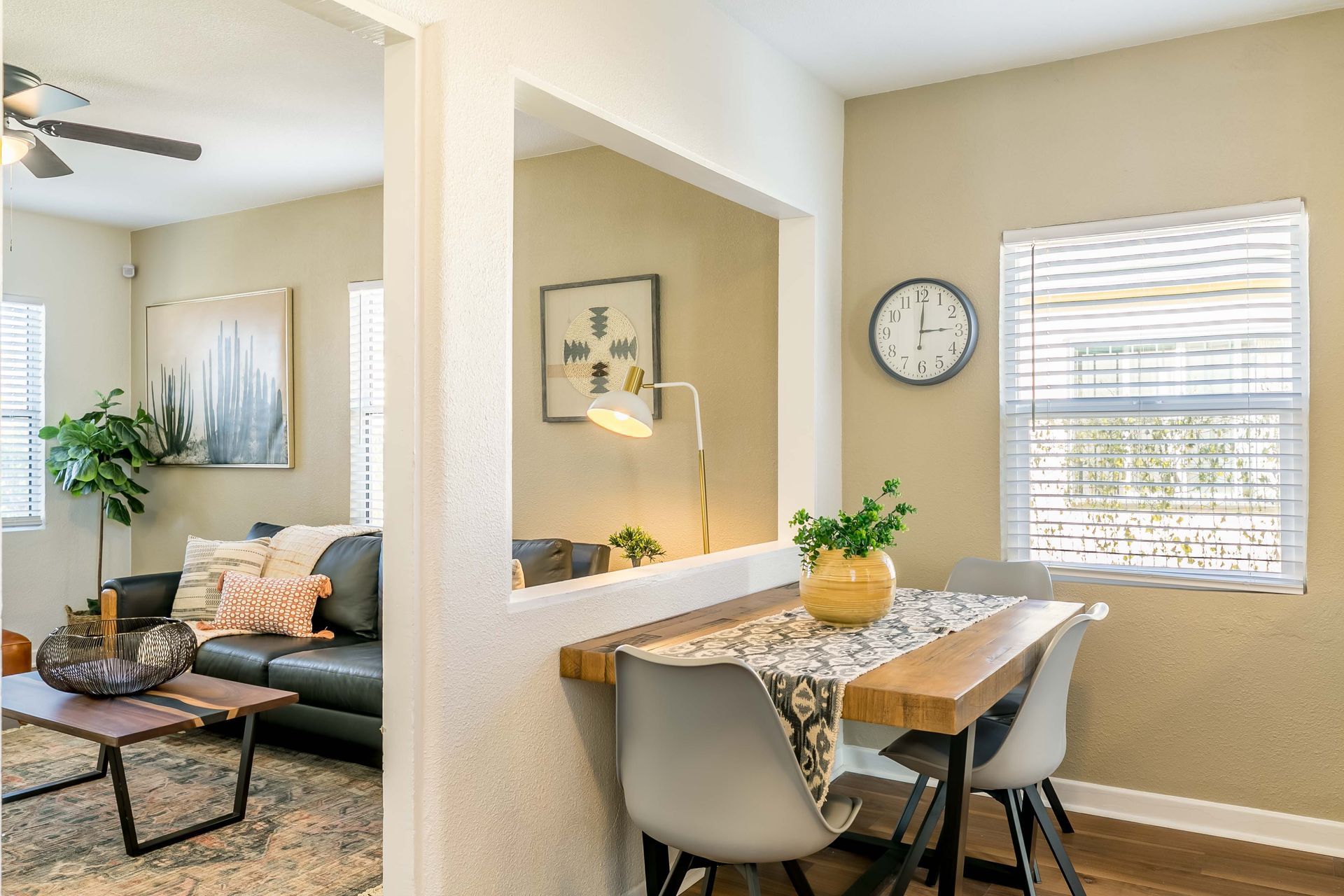 A living room with a table and chairs and a clock on the wall.