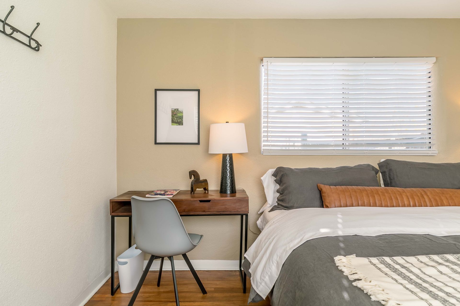 A bedroom with a bed , desk , chair and lamp.