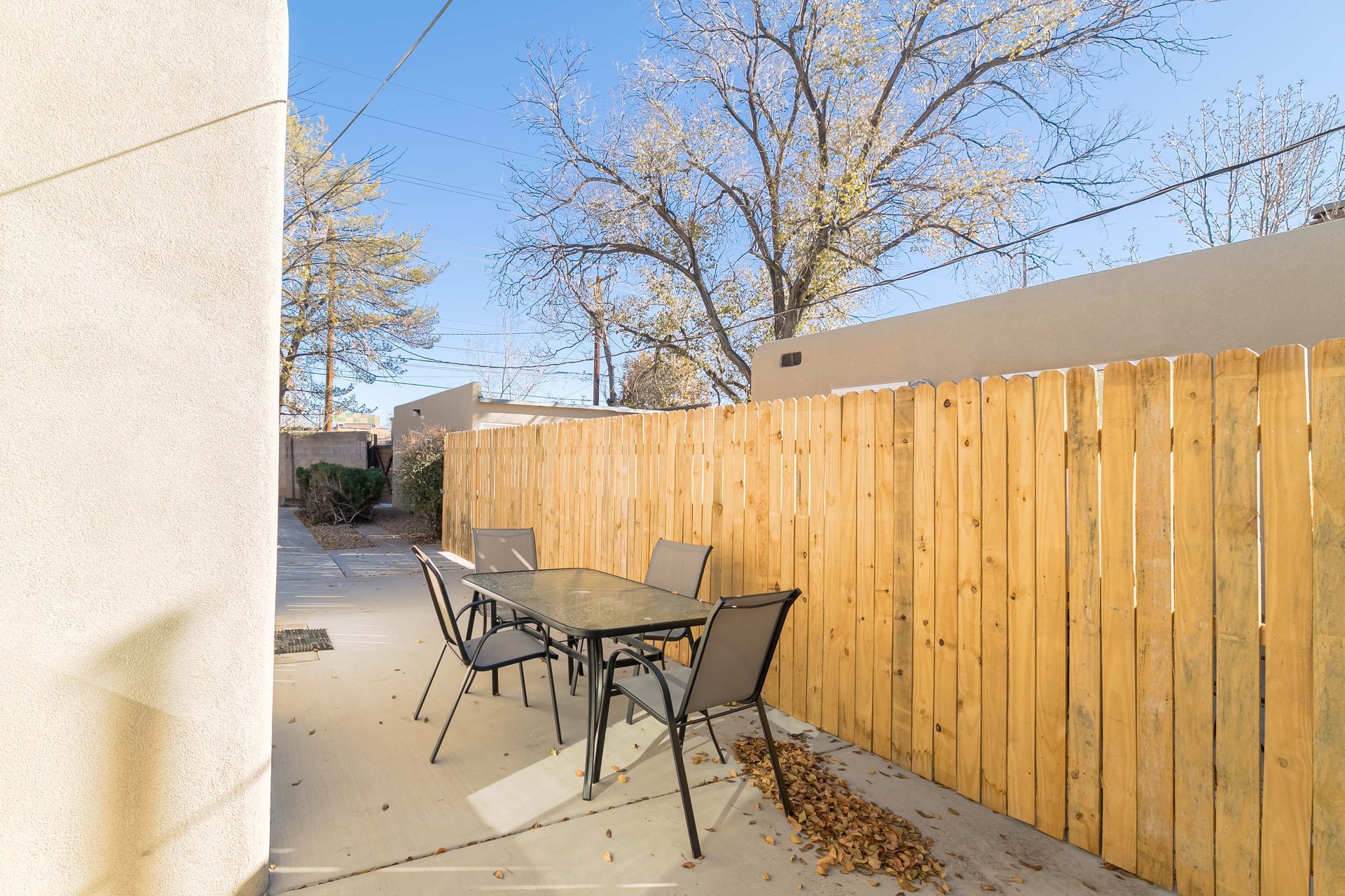 A wooden fence surrounds a patio with a table and chairs.