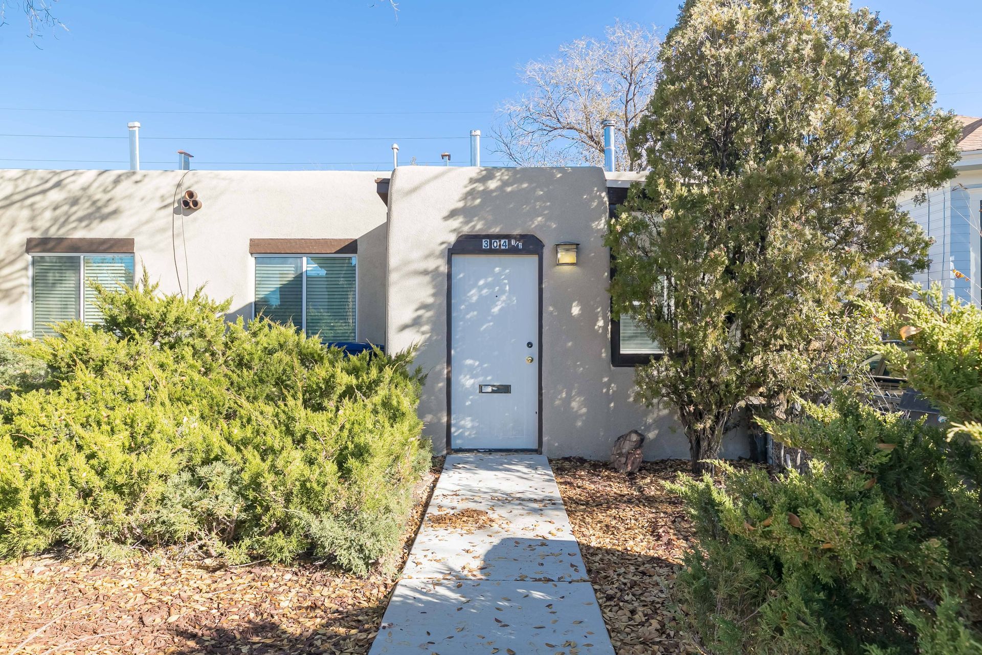 The front of a house with a white door and a walkway leading to it.