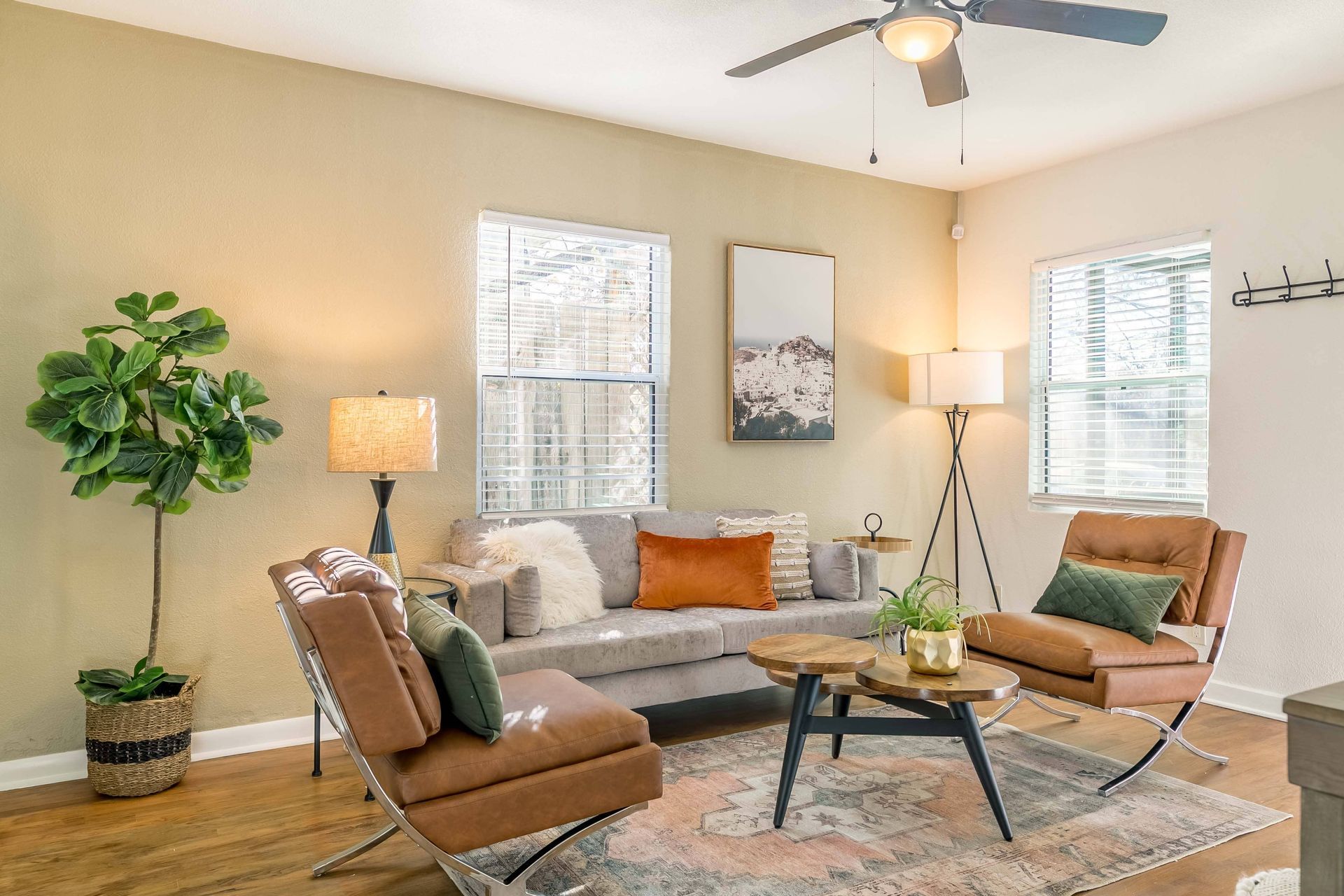A living room with a couch , chairs , coffee table and ceiling fan.