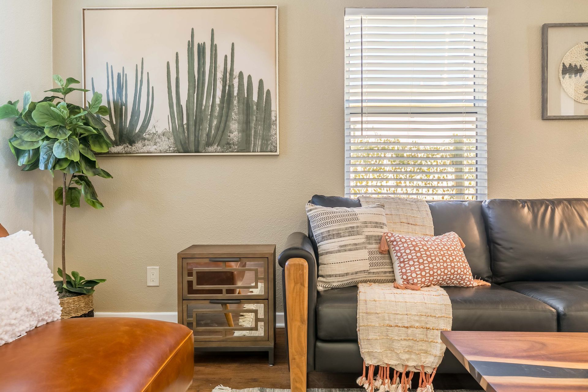 A living room with a couch , chair , coffee table and a painting on the wall.