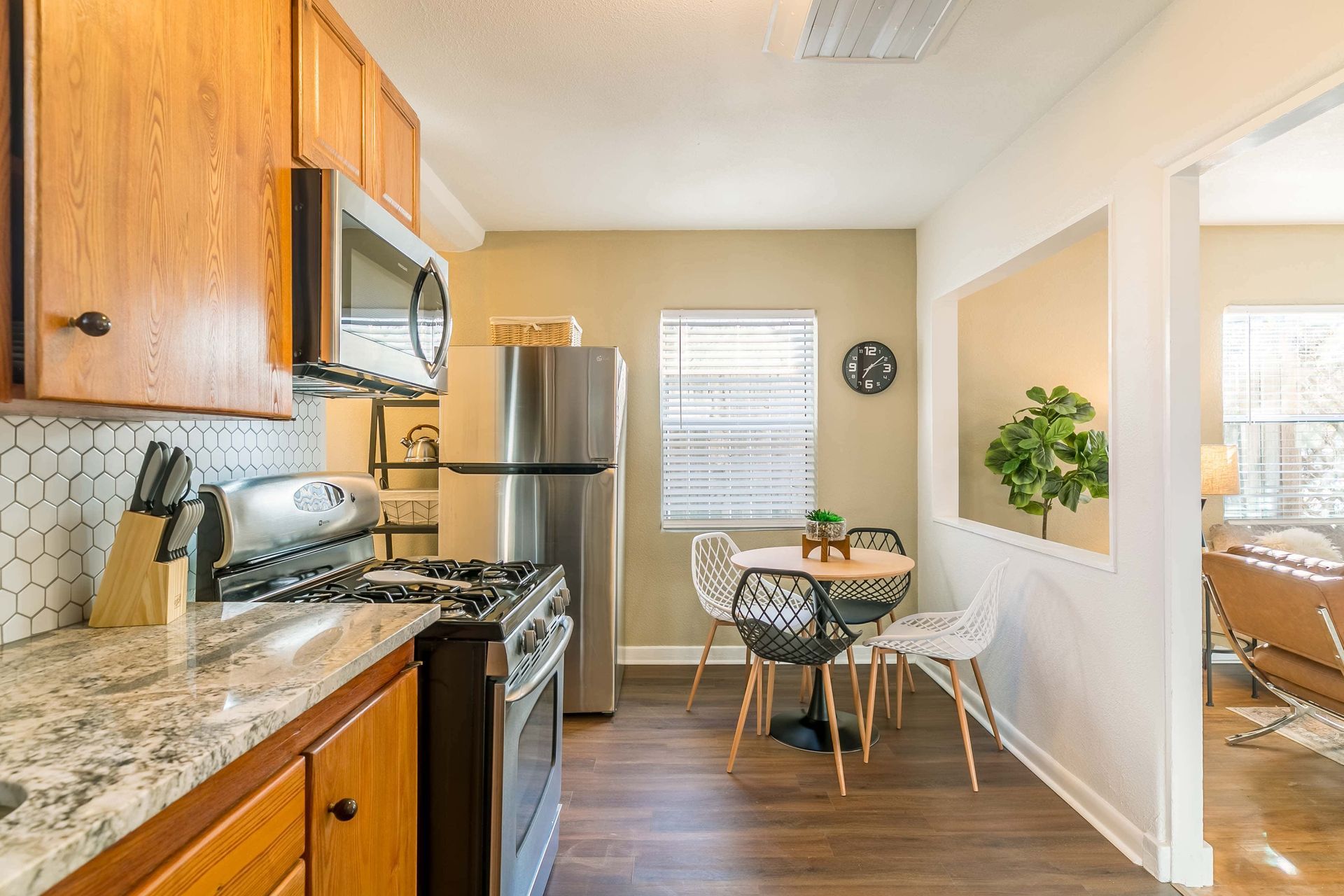 A kitchen with a stove , refrigerator , microwave , and table.