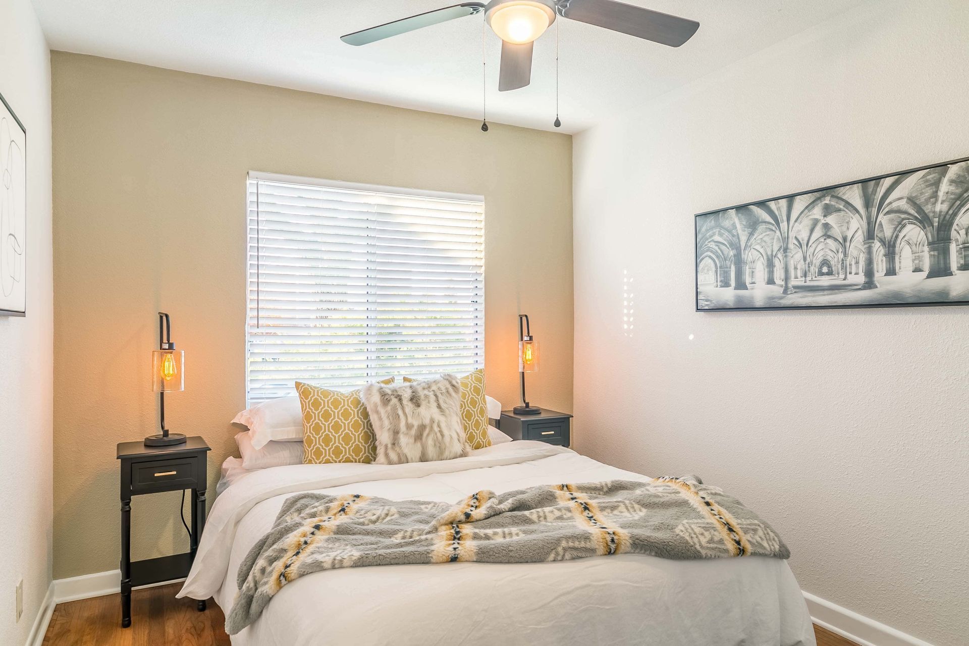 A bedroom with a bed , nightstands , and a ceiling fan.