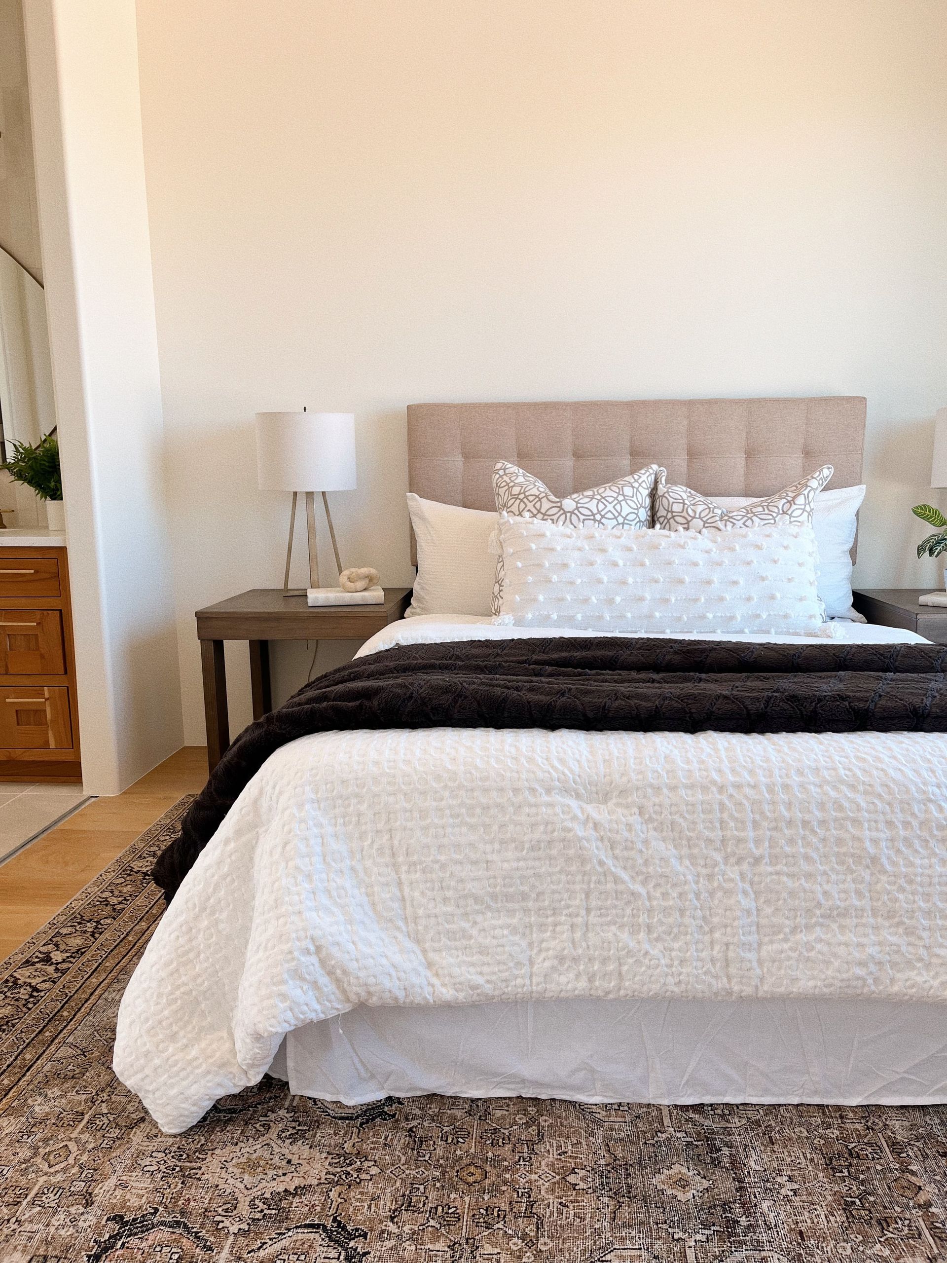 A bedroom with a bed , nightstand , lamp and rug.