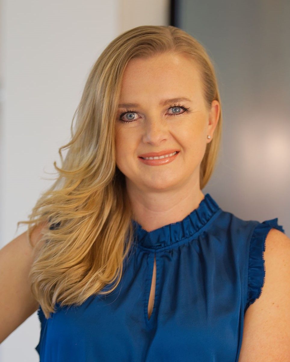 A woman in a blue shirt is smiling for the camera.