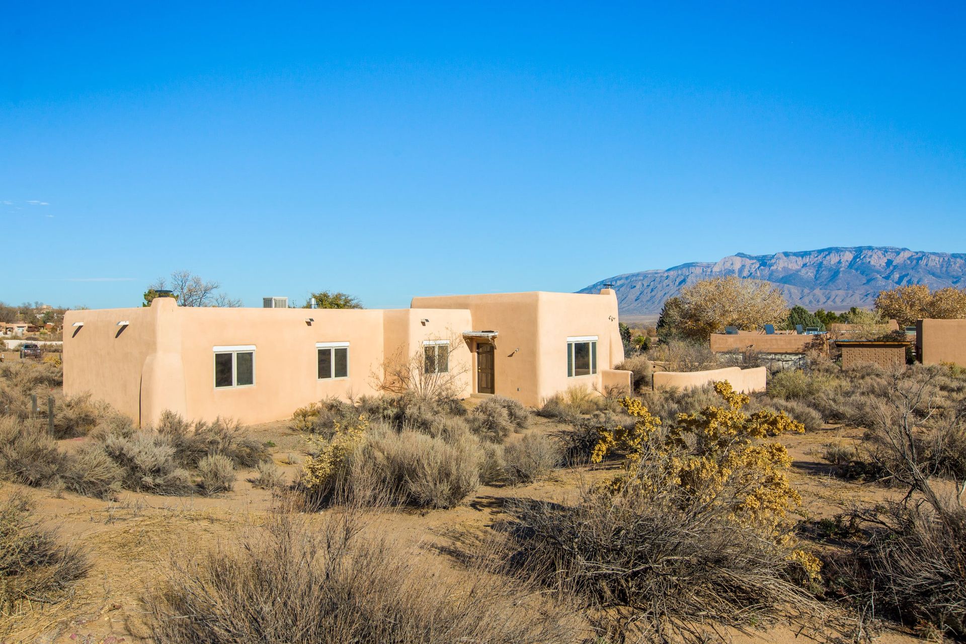 A house in the middle of a desert with mountains in the background.