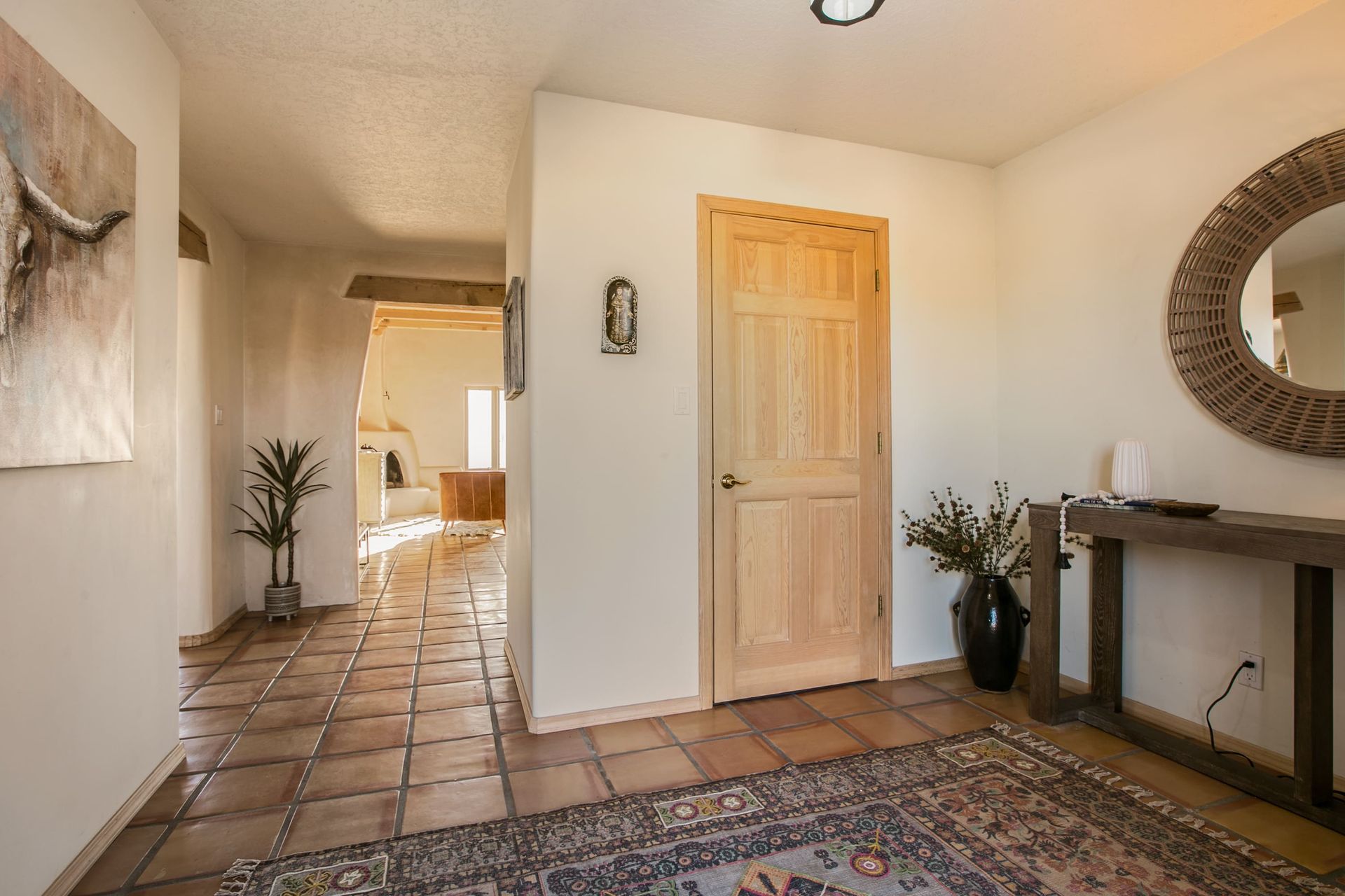 A hallway in a house with a wooden door and a rug.