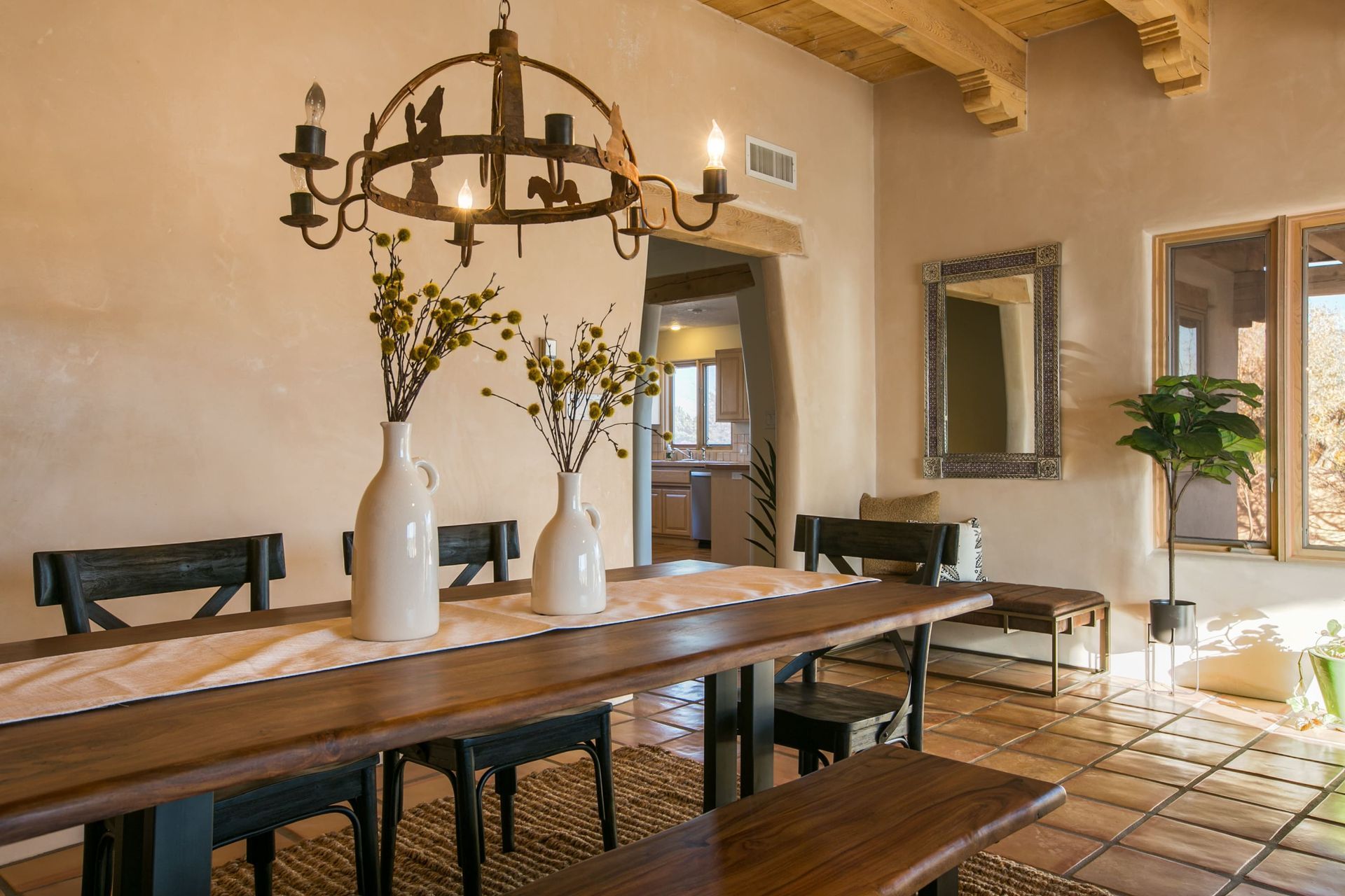 A dining room table with vases on it and a chandelier hanging from the ceiling.