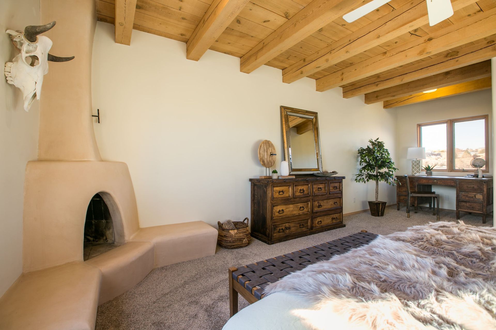 A bedroom with a fireplace , dresser , mirror and bed.