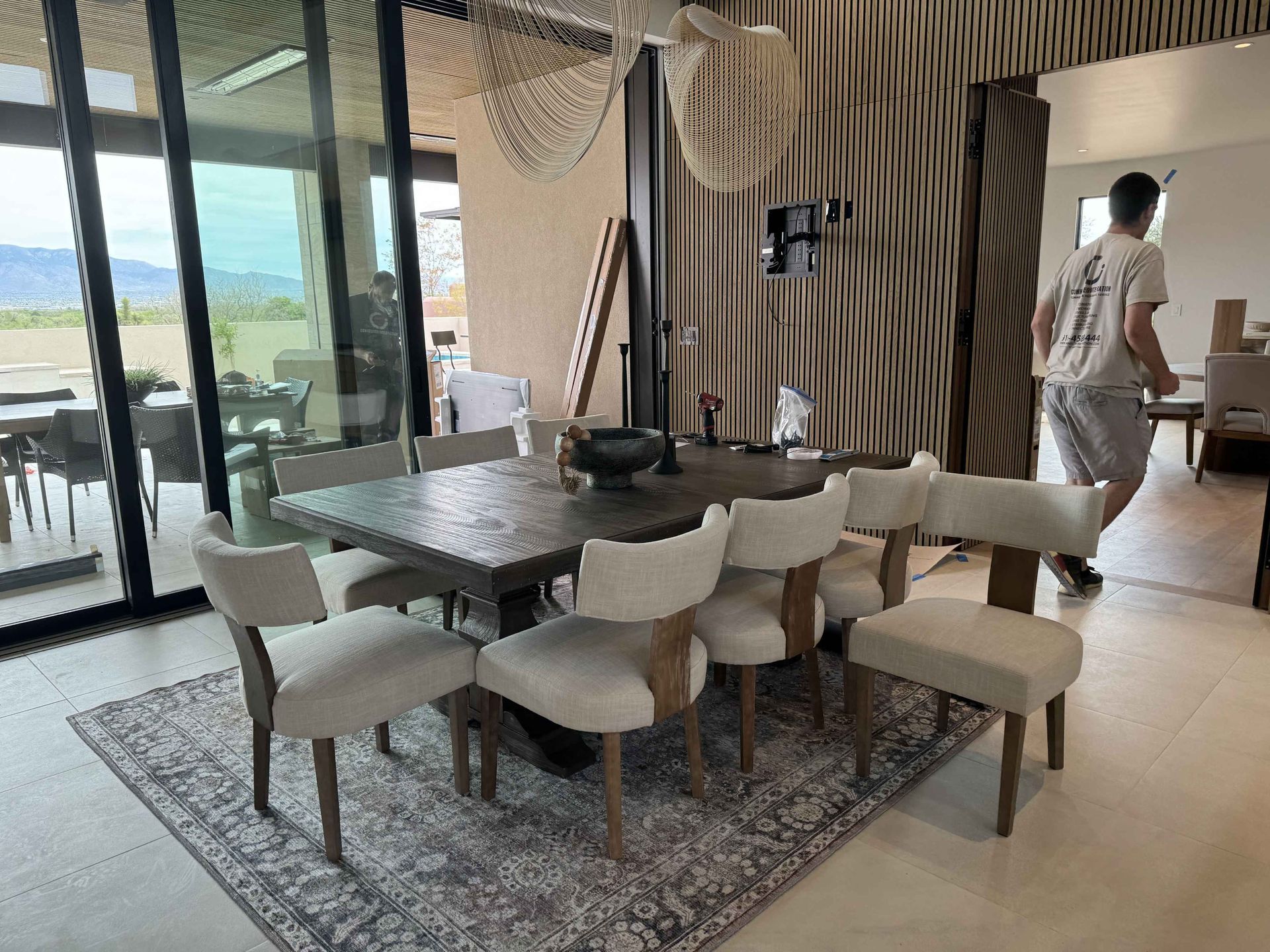 A man is standing in front of a dining room table and chairs.