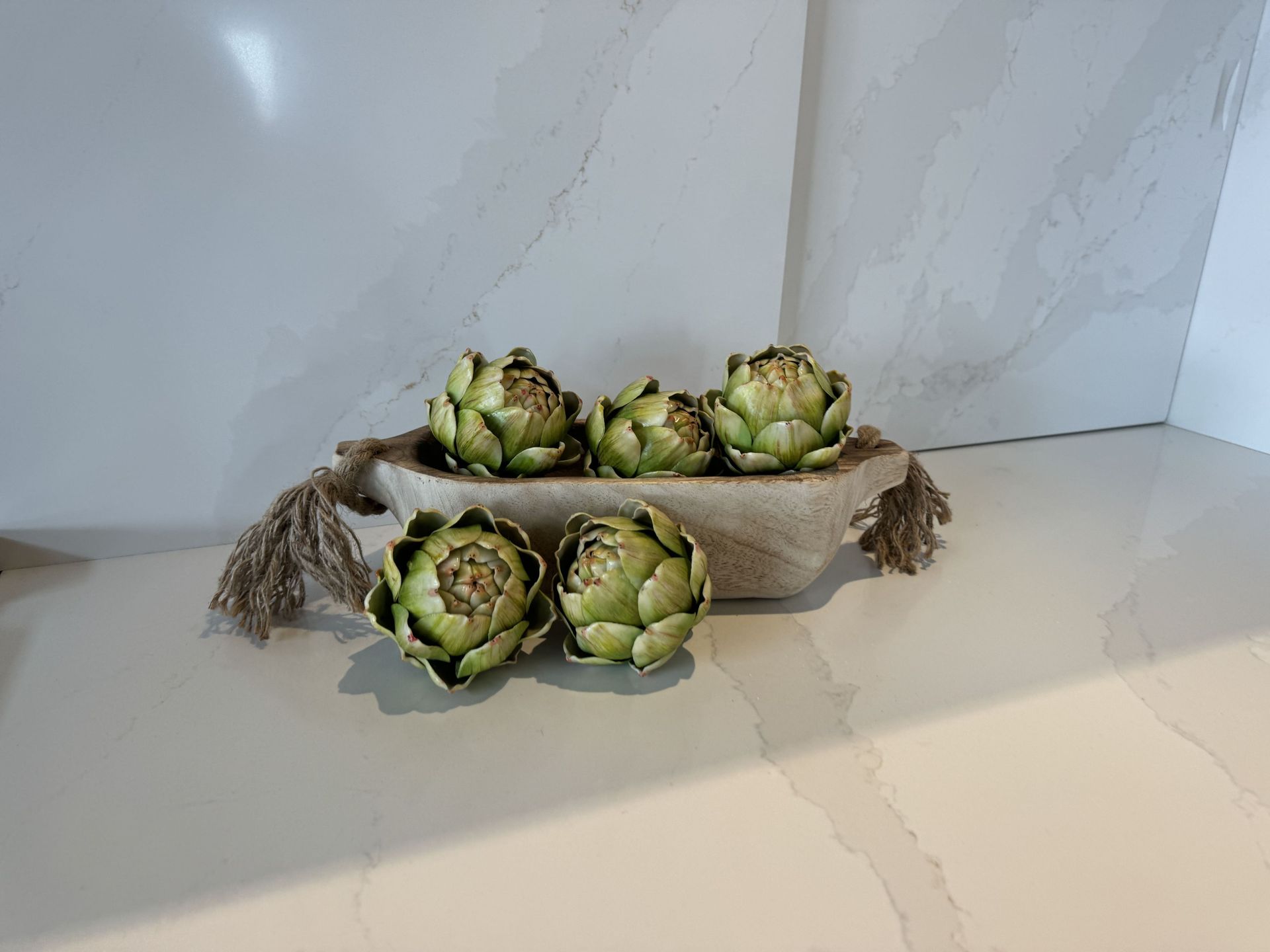 Three artichokes are sitting in a bowl on a counter.