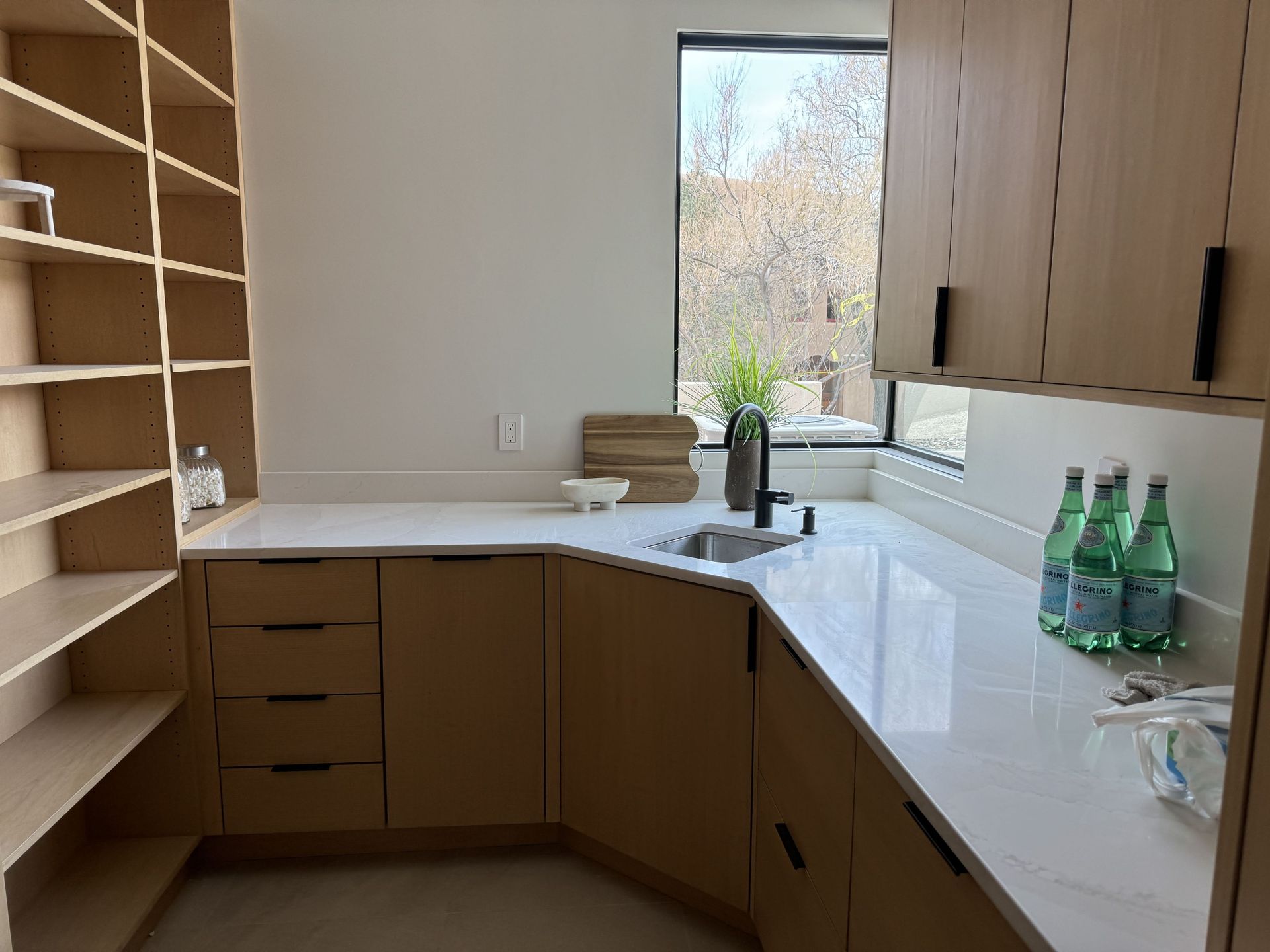 A kitchen with wooden cabinets , white counter tops , and a sink.