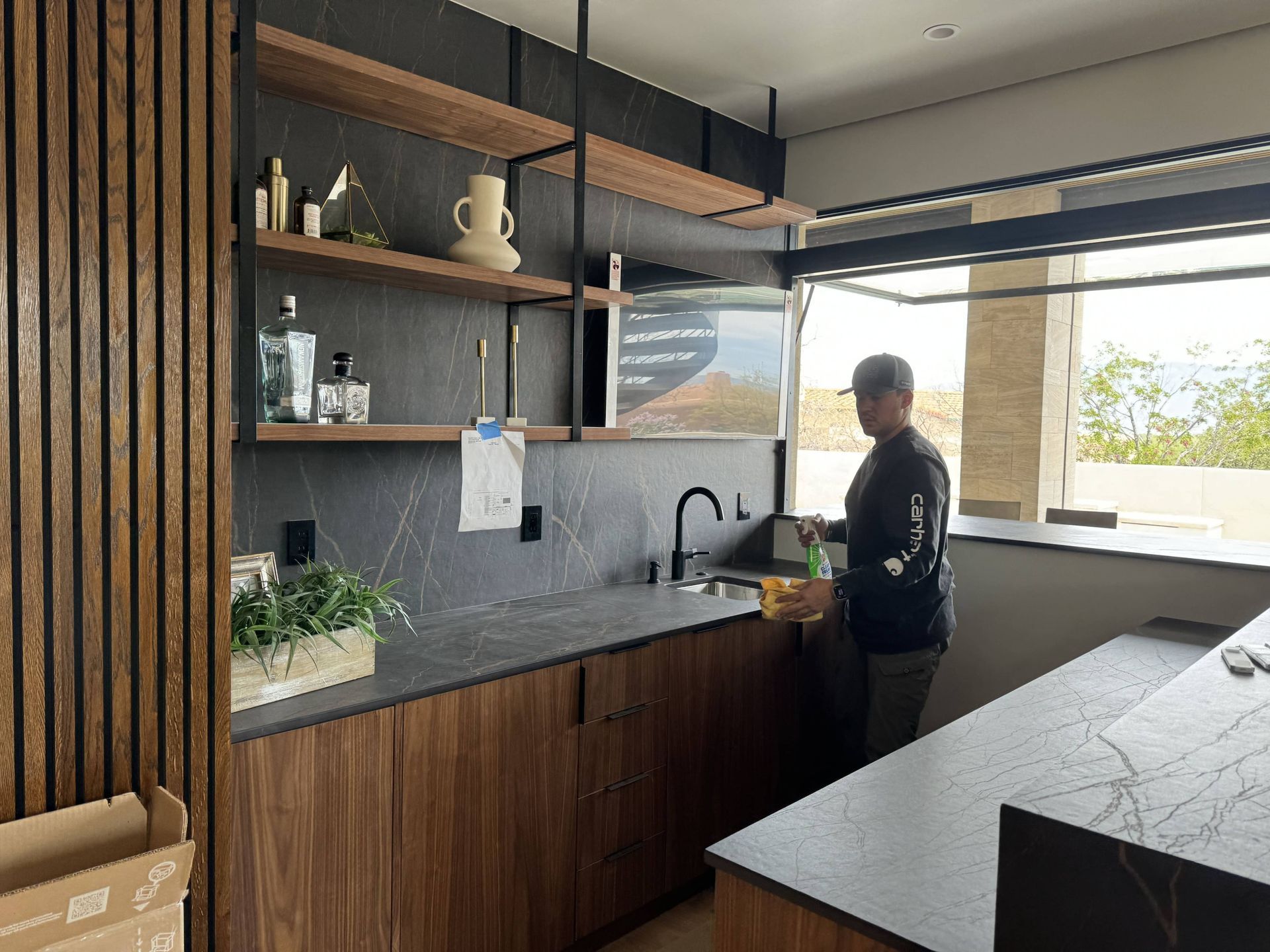 A man is standing in a kitchen next to a sink.