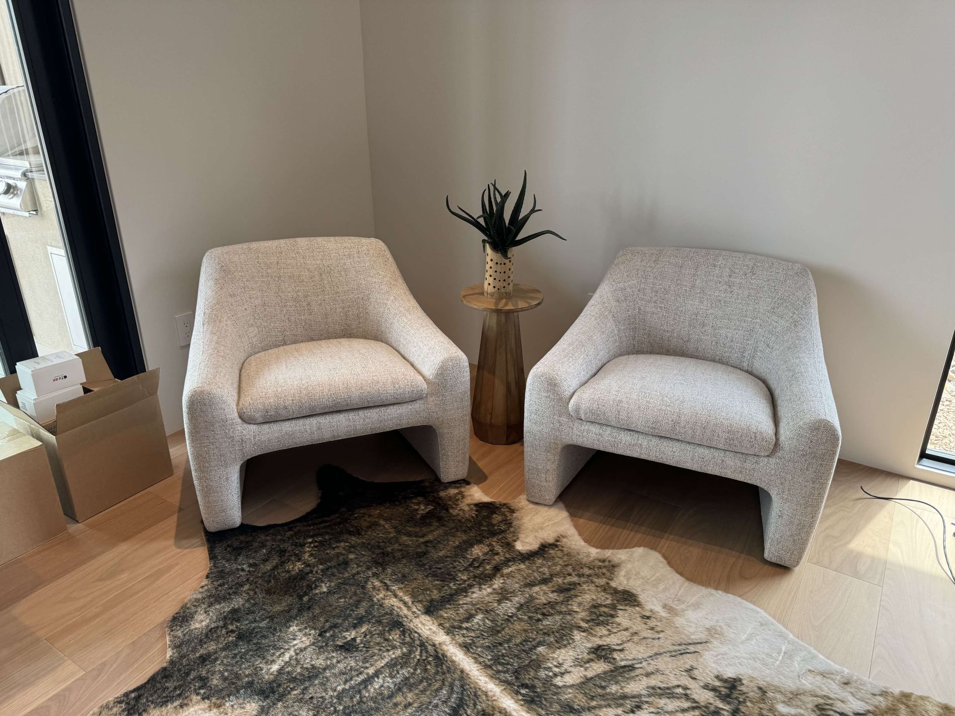 Two chairs are sitting next to a cowhide rug in a living room.