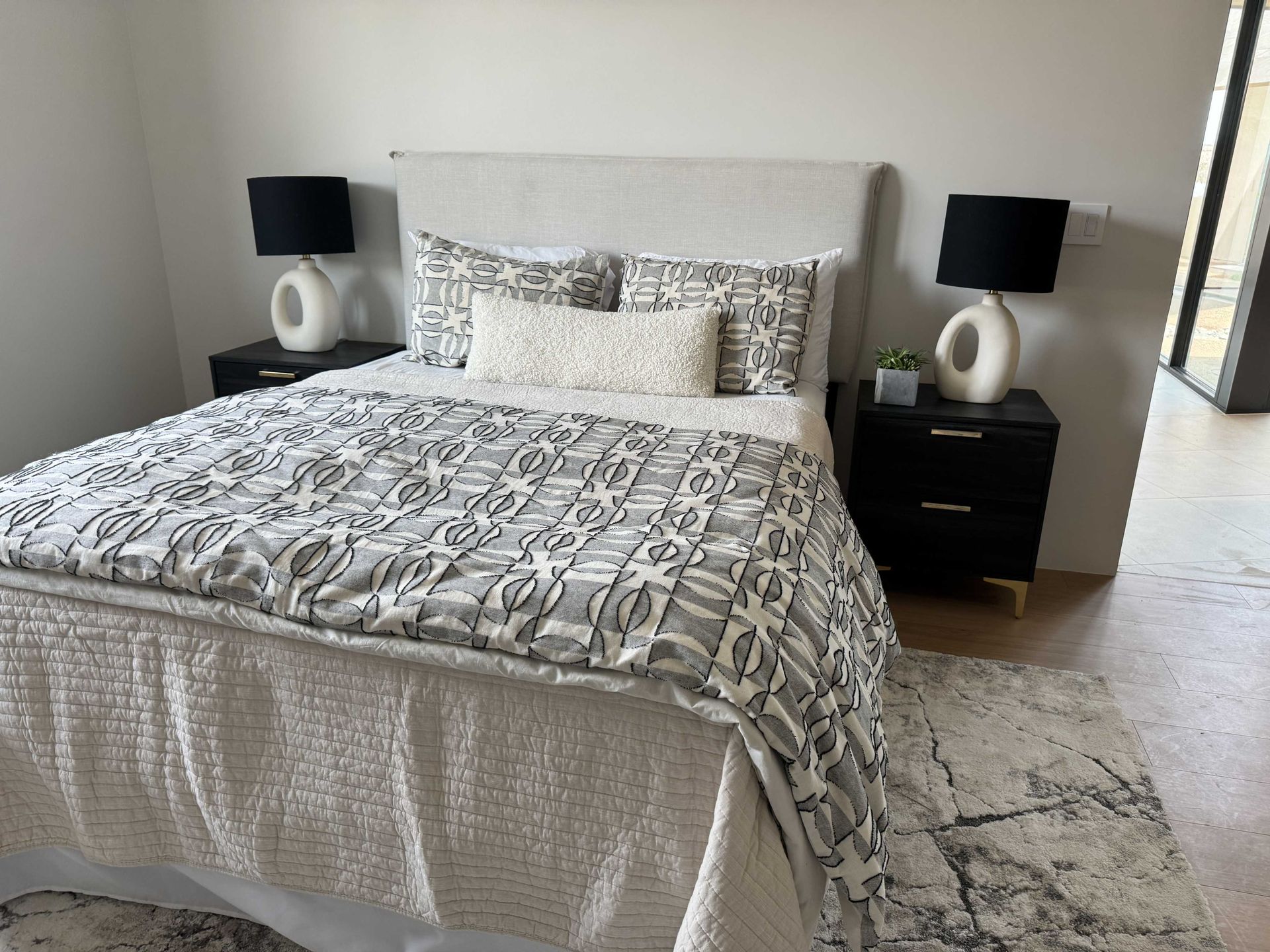 A bedroom with a bed , two nightstands and two lamps.
