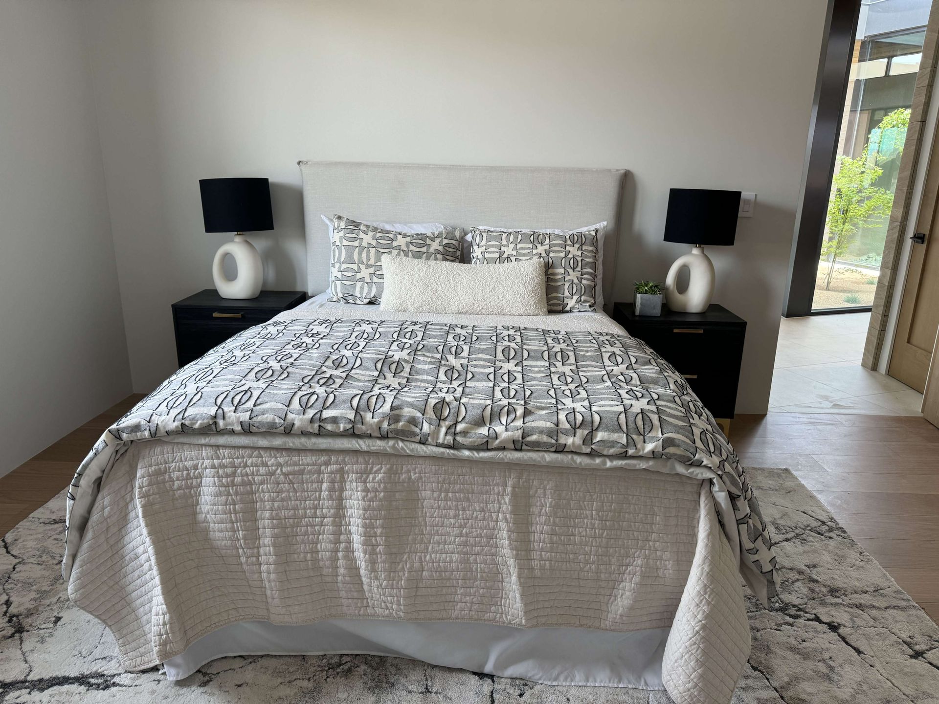 A bedroom with a bed , nightstands , lamps and a rug.