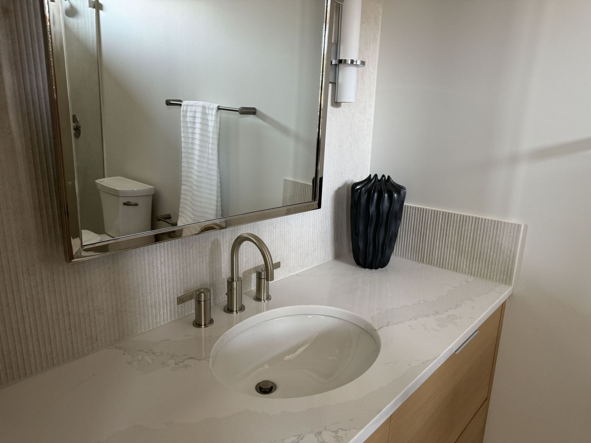 A bathroom with a sink , mirror and toilet.