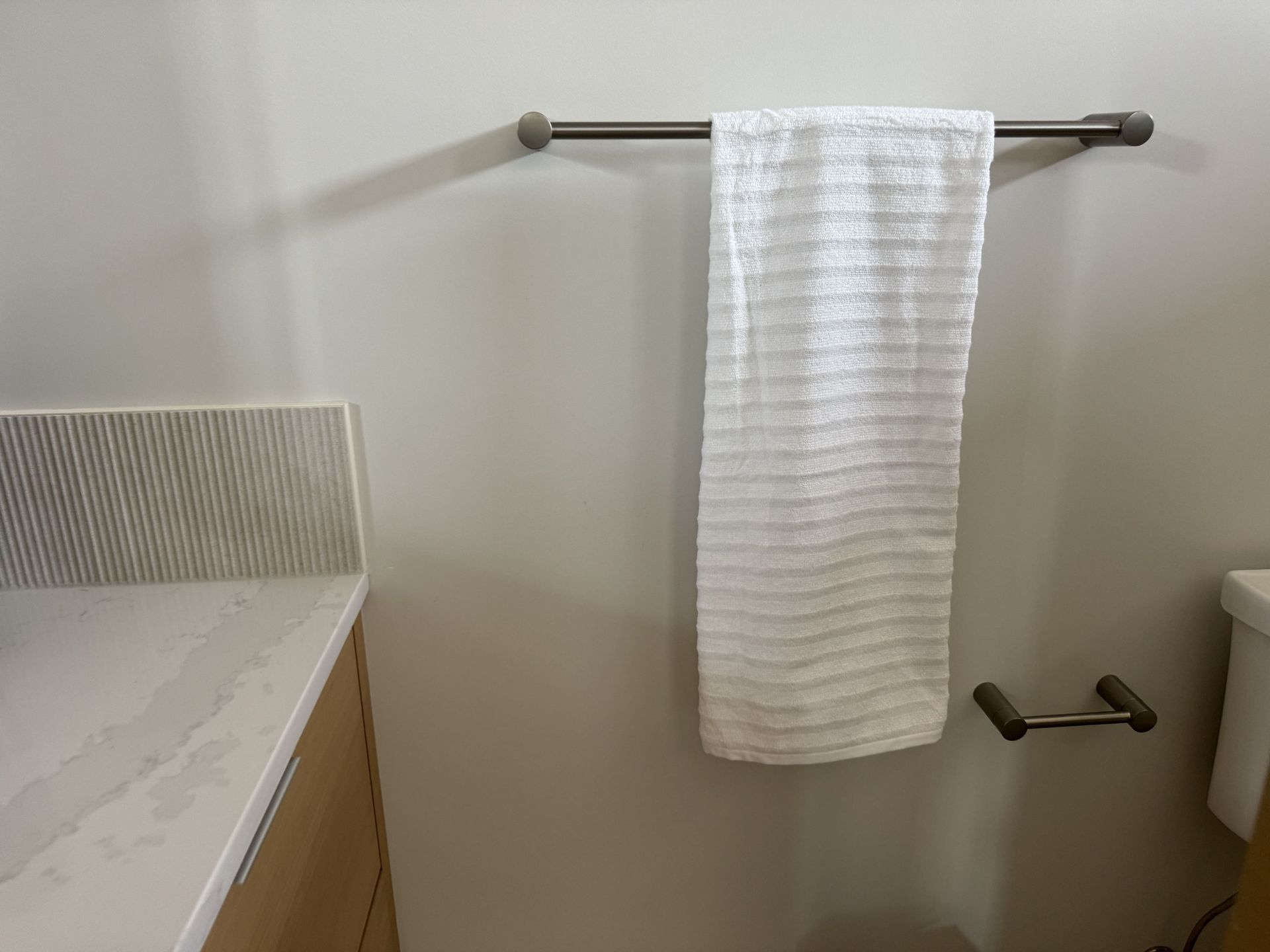 A white towel is hanging on a towel rack in a bathroom.
