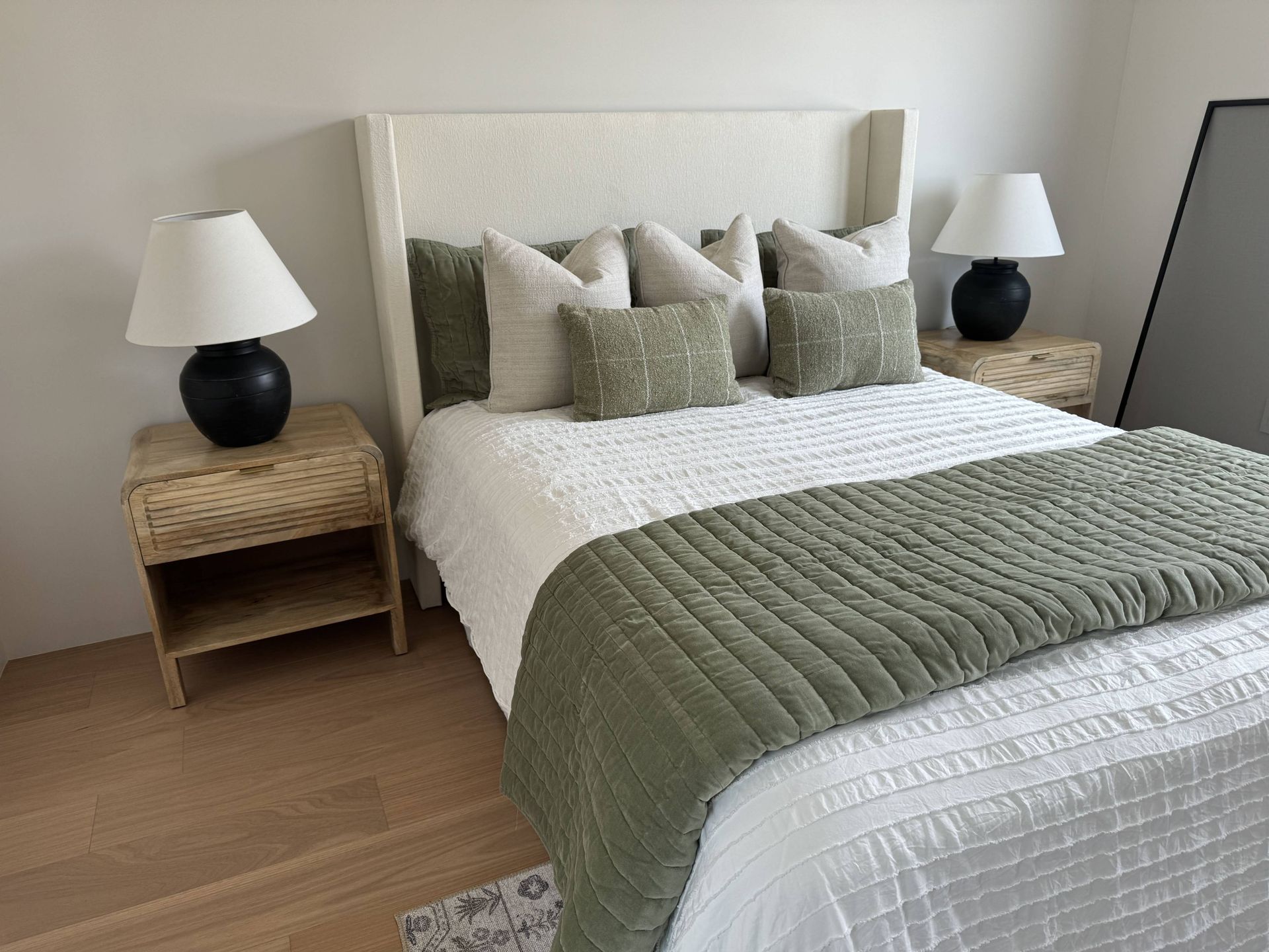 A bedroom with a bed , two nightstands , two lamps and a mirror.