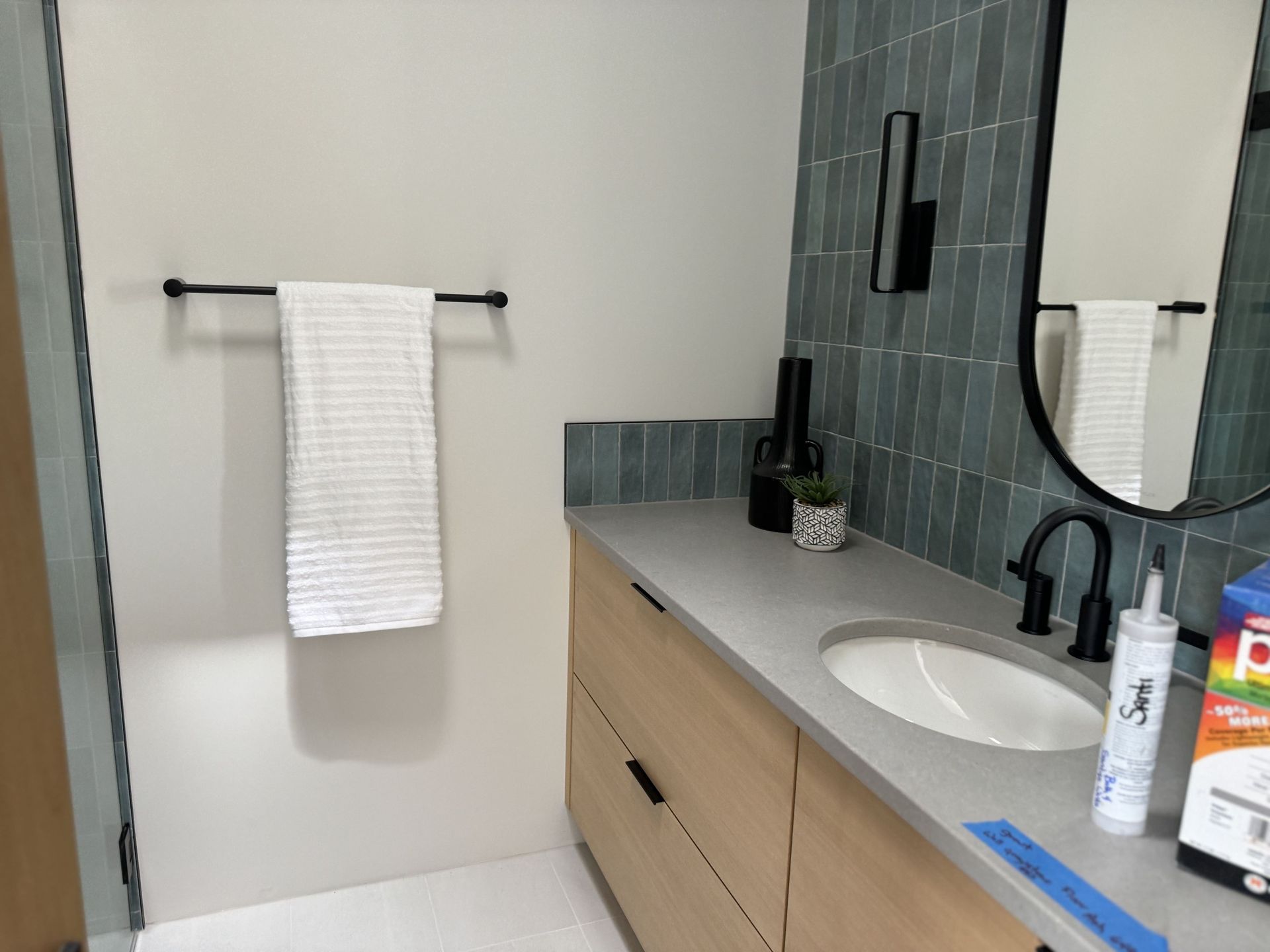 A bathroom with a sink , mirror and towel rack.