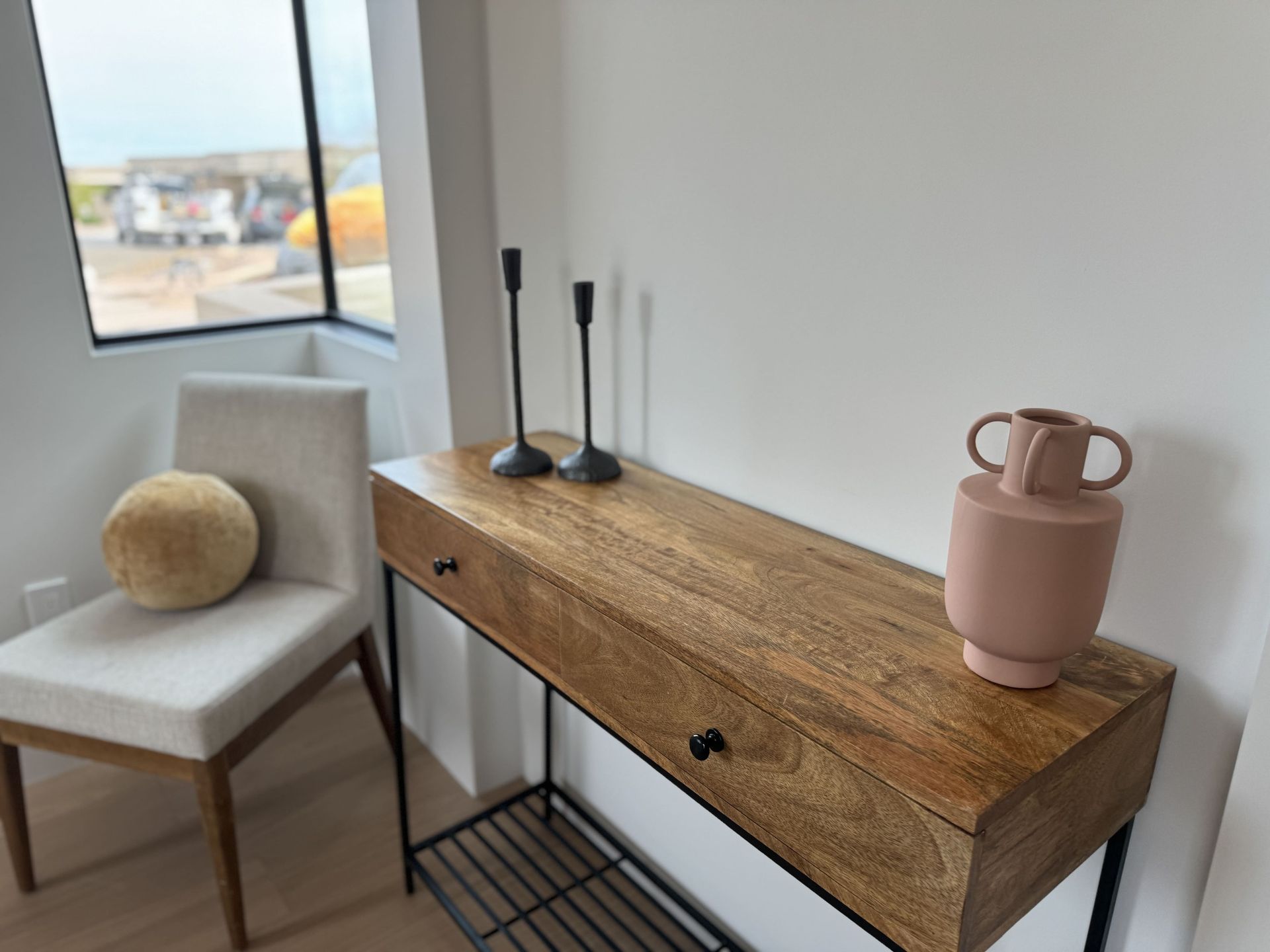 A wooden table with candles and a vase on it next to a chair.