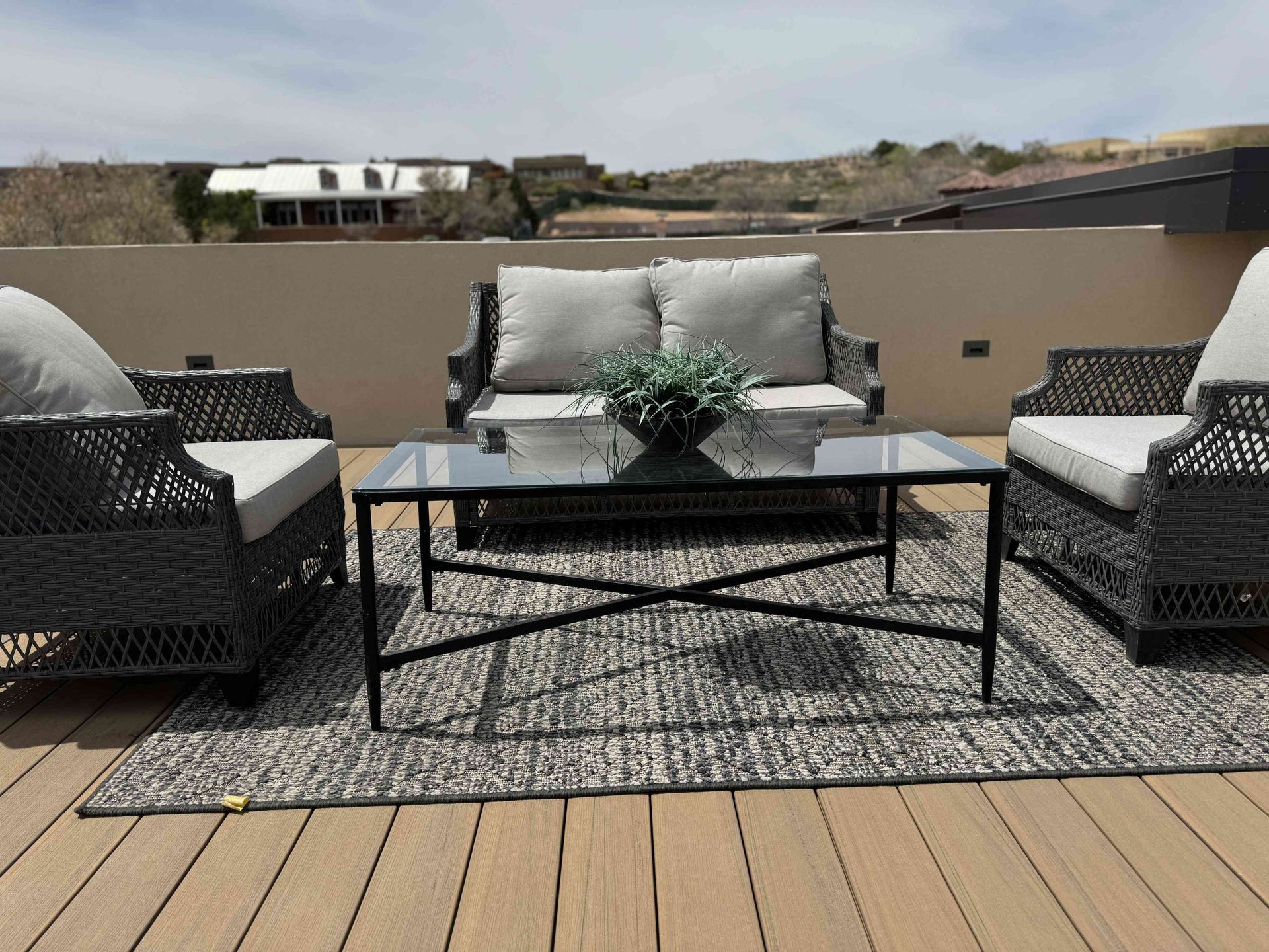 A patio set with a couch , chairs and a coffee table on a wooden deck.