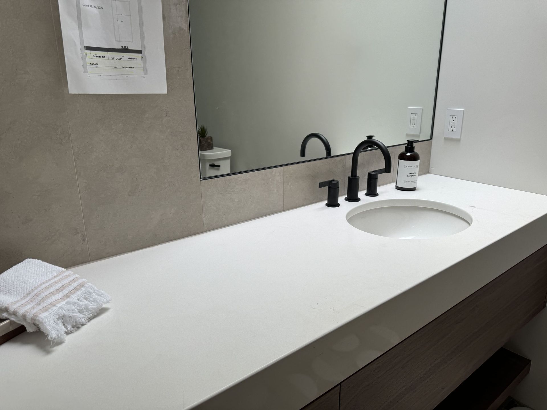 A bathroom with a sink , mirror and towel on the counter.