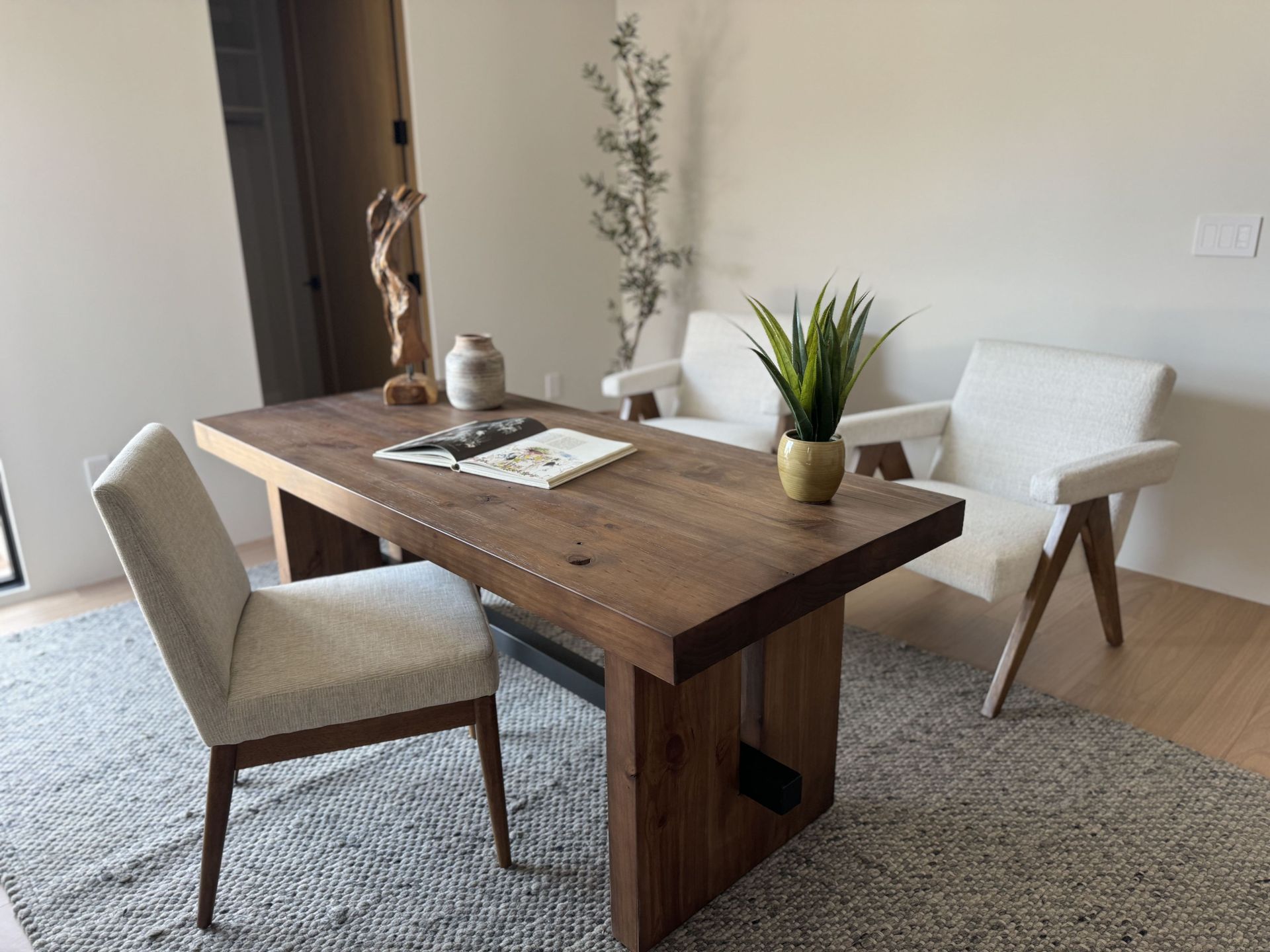 A wooden table with two chairs and a plant on it in a living room.