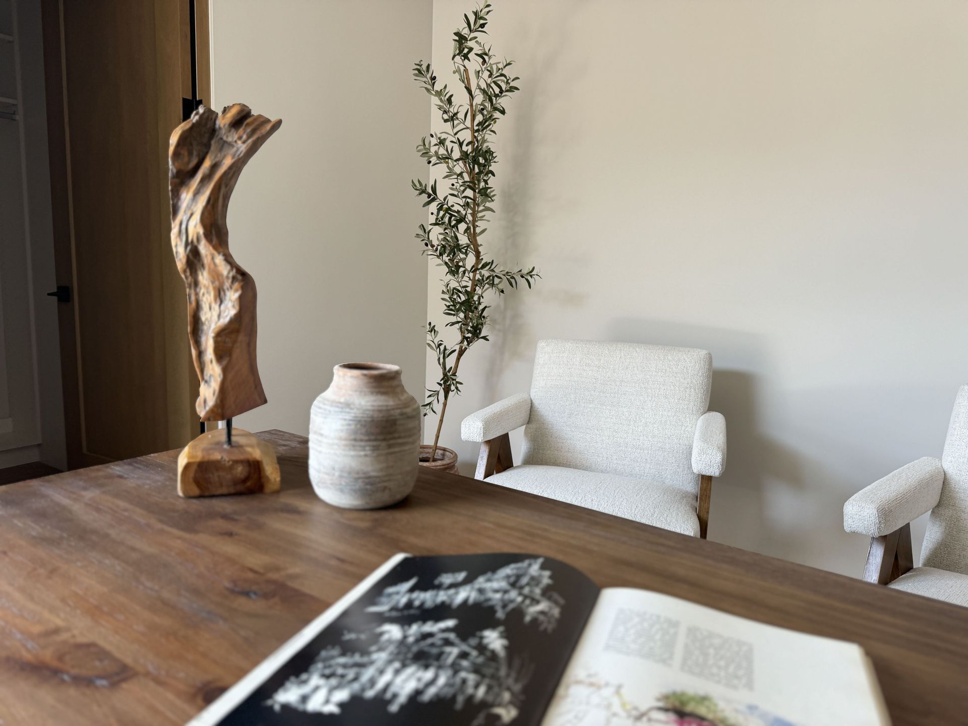 A wooden table with a book and a vase on it.