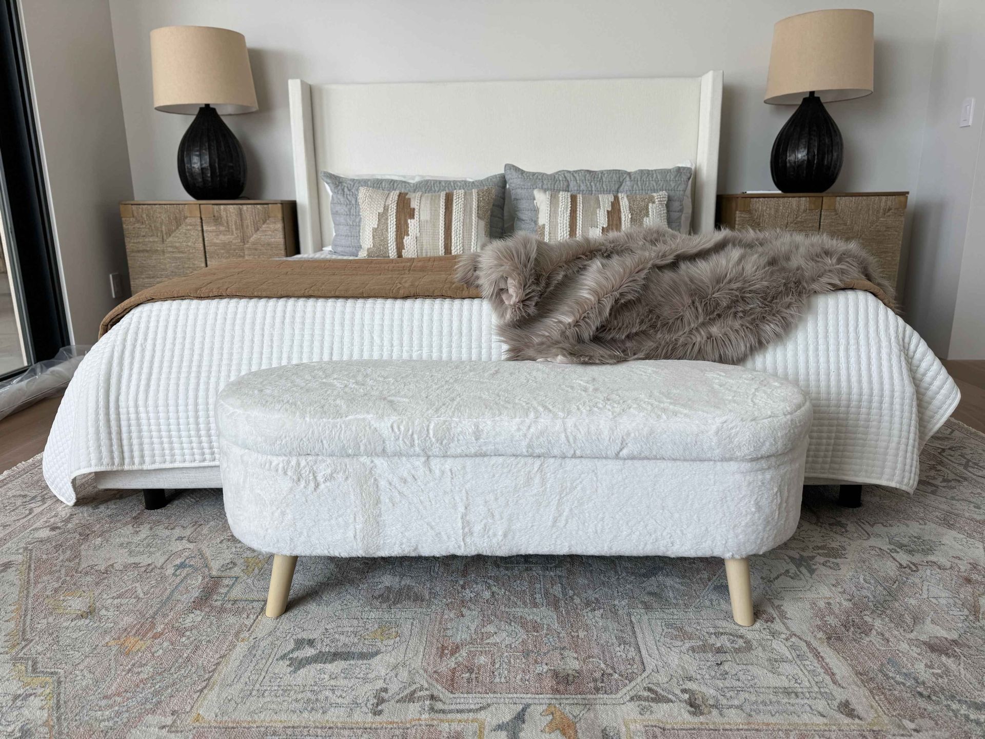 There is a bench in the middle of the bedroom next to the bed.
