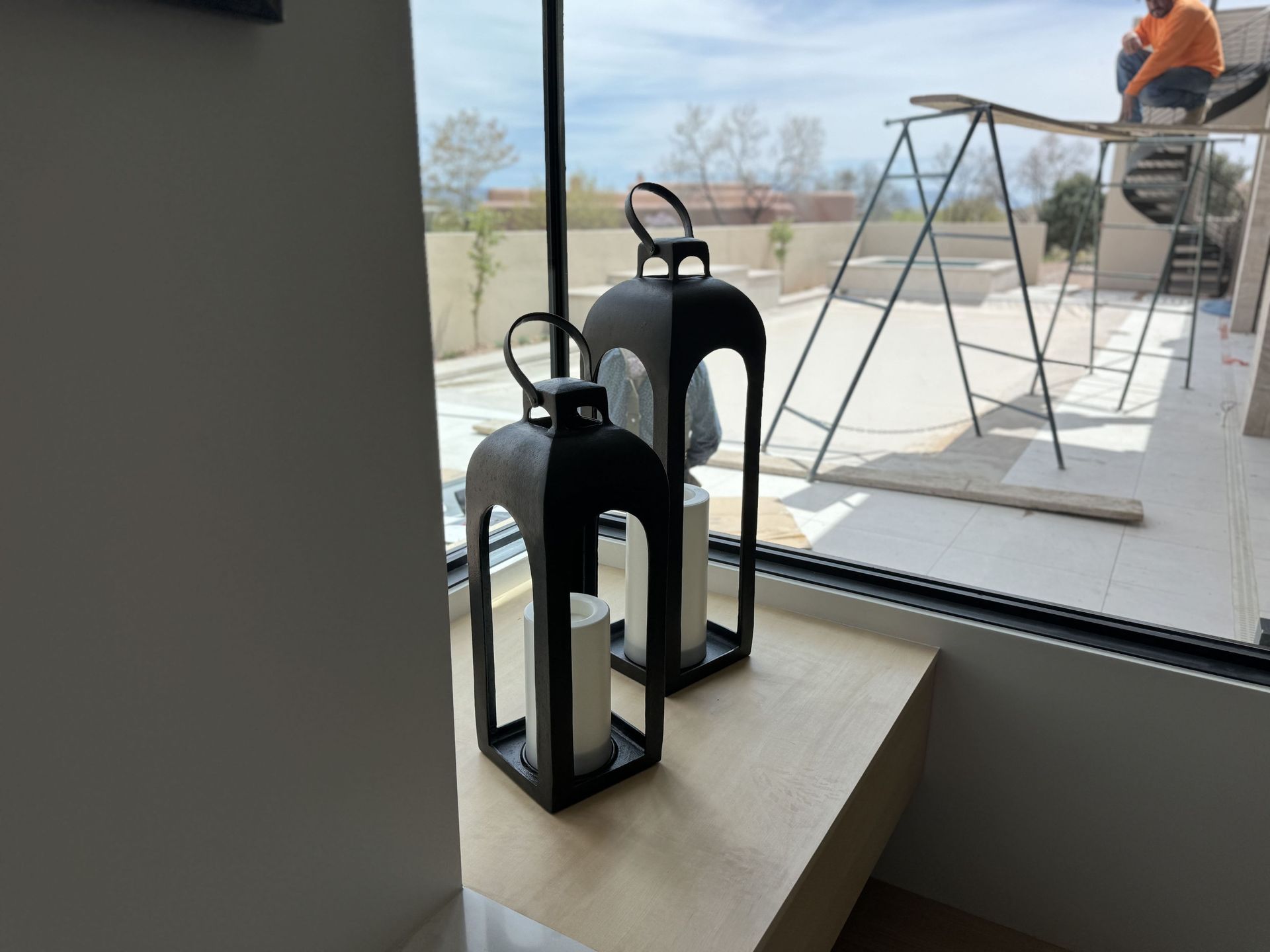 Two black lanterns are sitting on a table in front of a window.